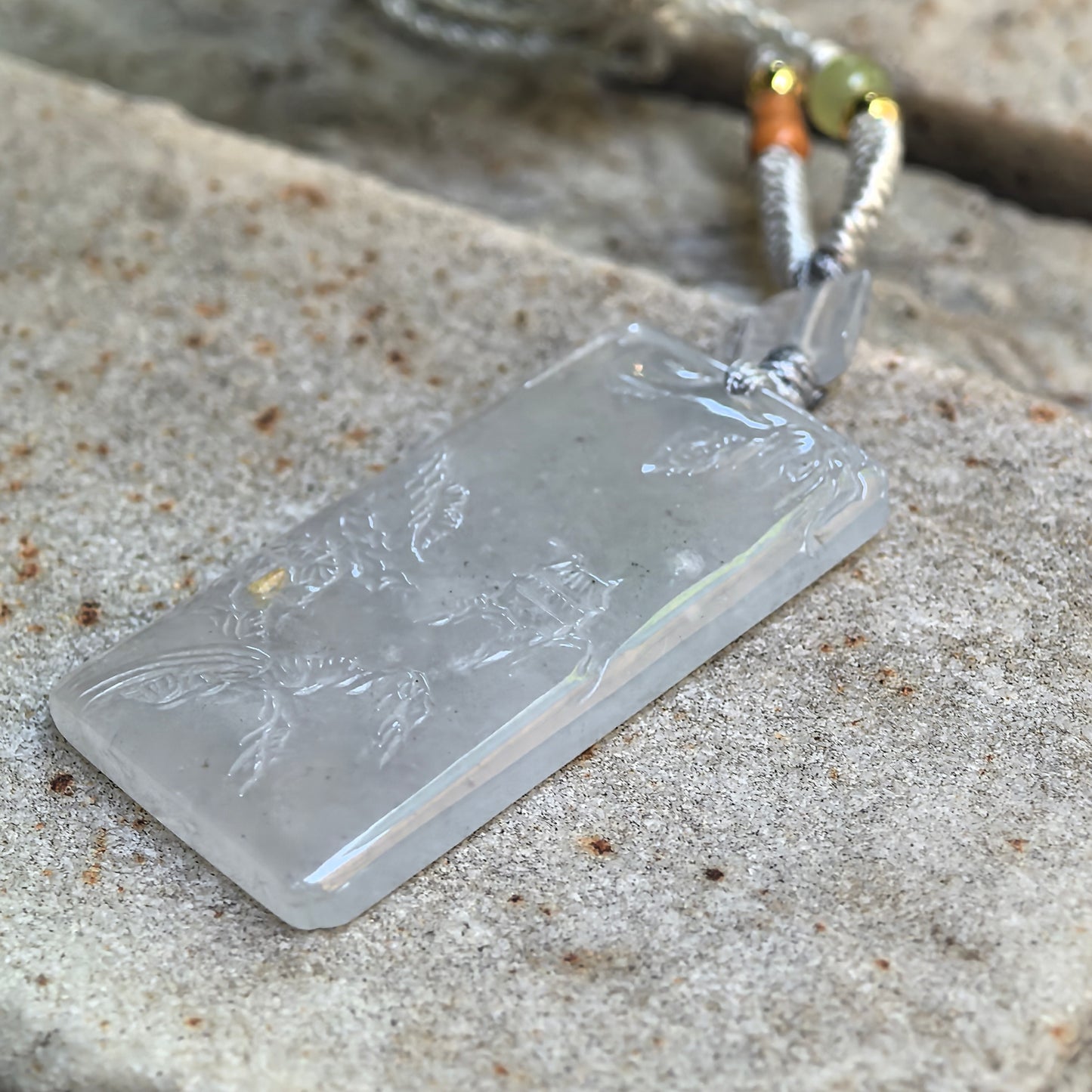 Side view of slim white jadeite landscape pendant showing polished edge and natural cloudy texture.
