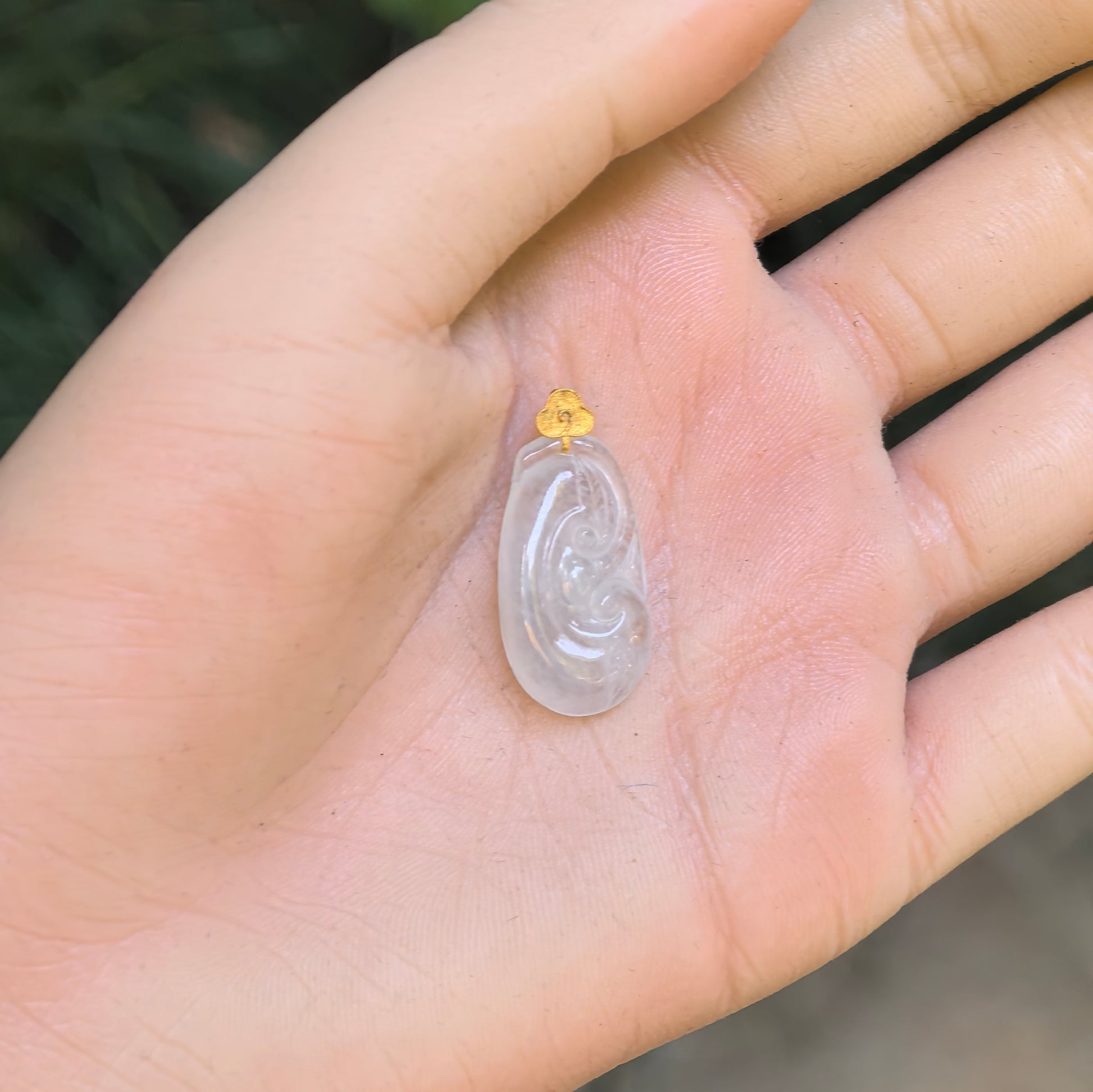 Natural Grade-A glutinous icy white Ruyi jadeite pendant shown on palm with 18K gold bail.
