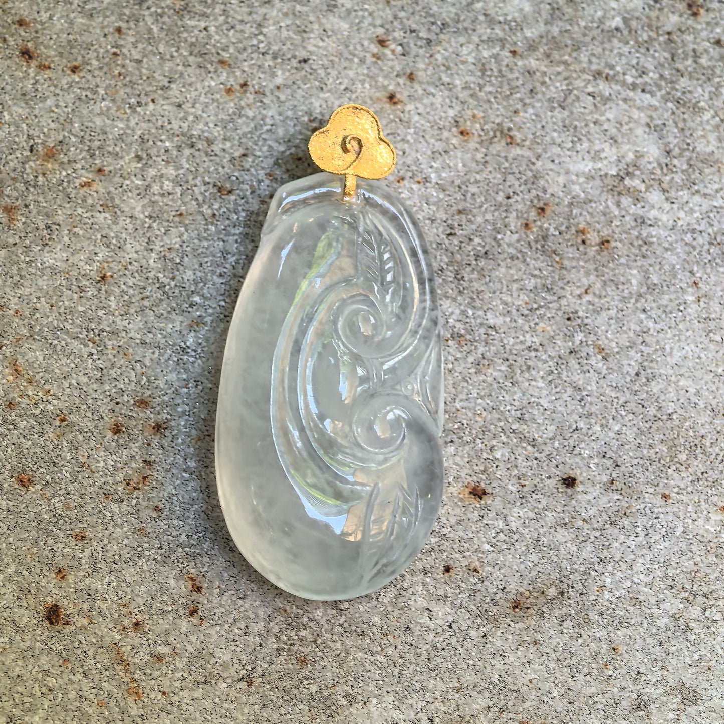 Close-up of white Ruyi jadeite pendant with flowing scroll and leaf carving details.