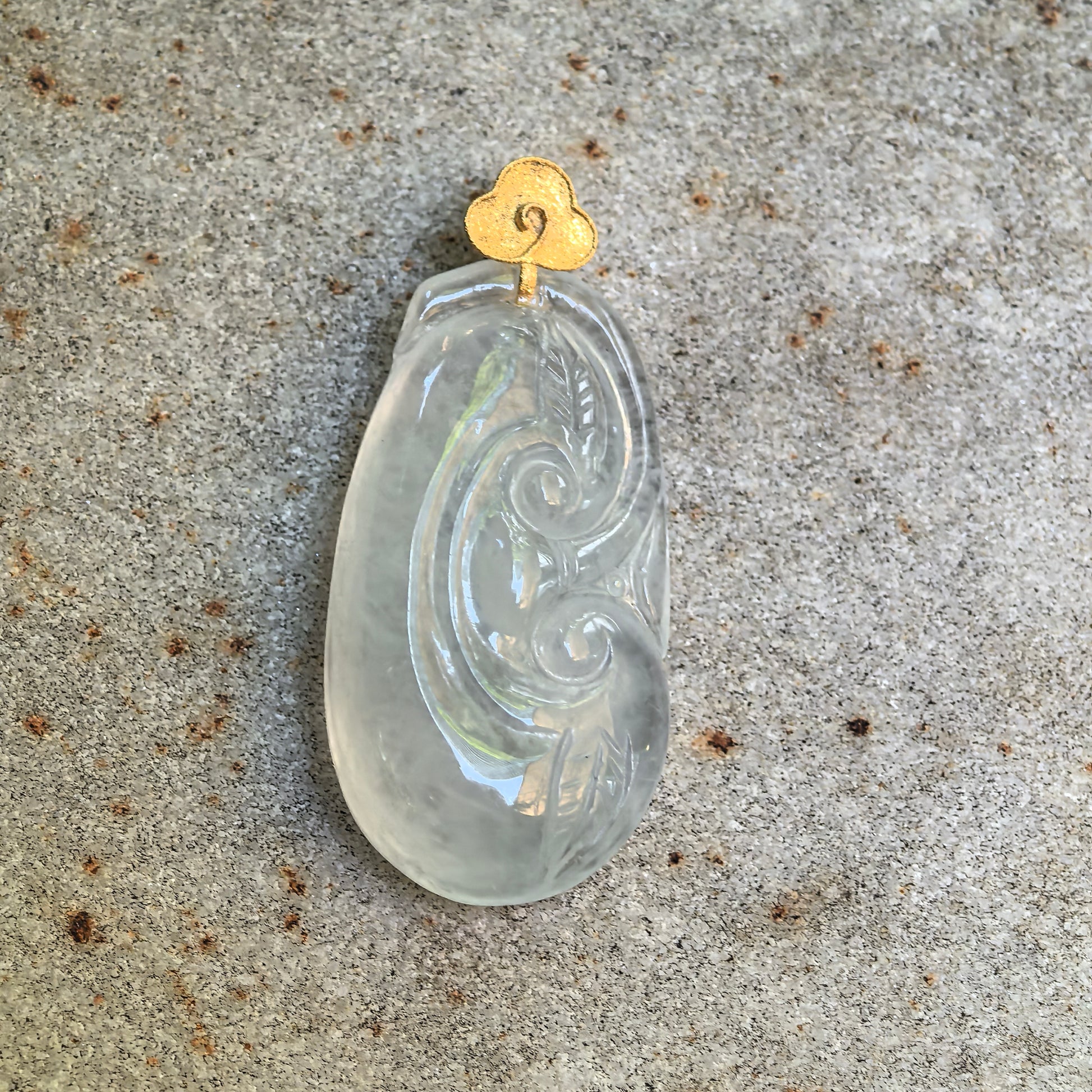 Close-up of white Ruyi jadeite pendant with flowing scroll and leaf carving details.