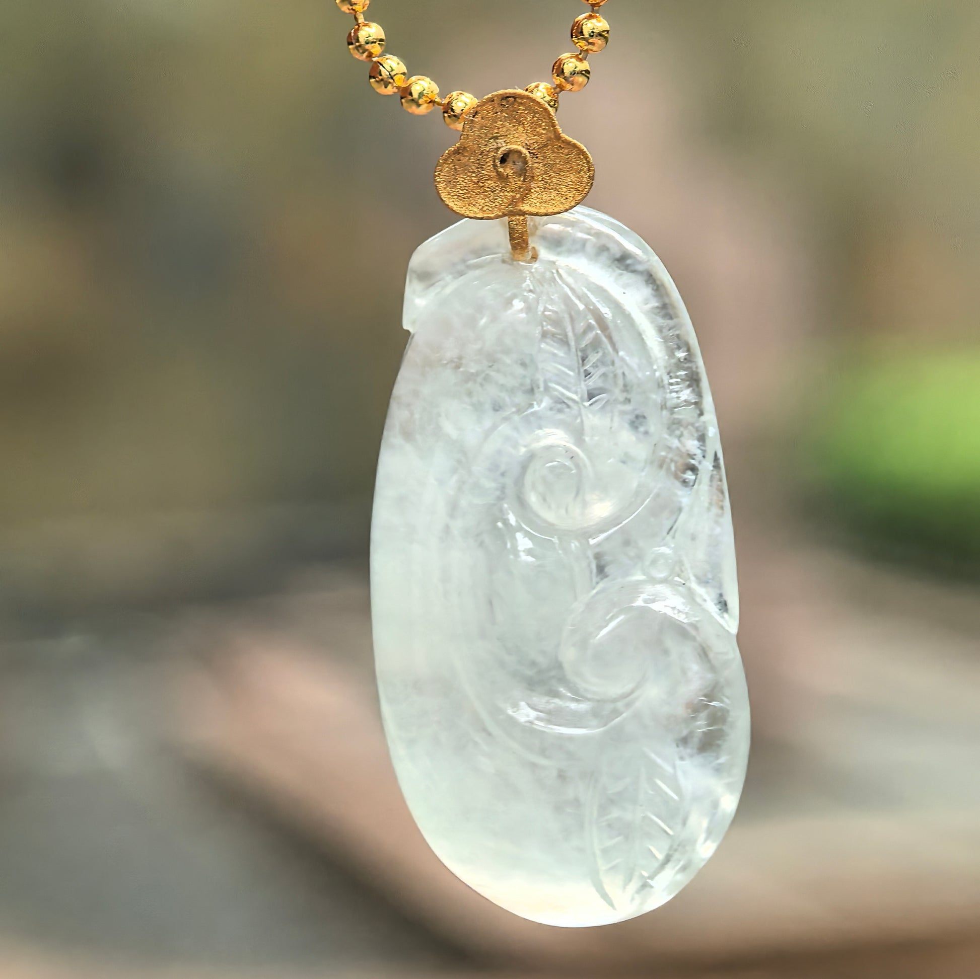 Natural Grade-A Burmese jadeite Ruyi pendant in white and pale green tone under soft light.