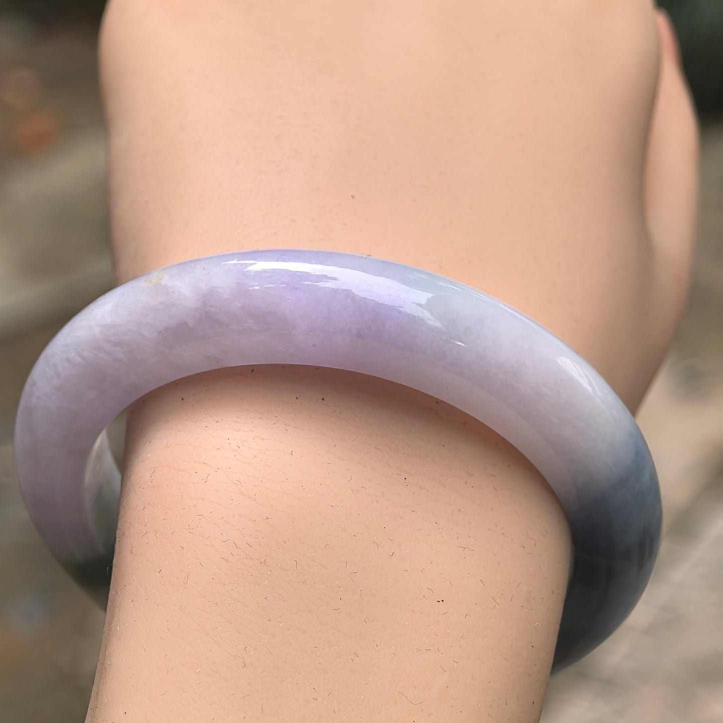 Close-up of lavender and denim blue jadeite bangle showing smooth polished surface.
