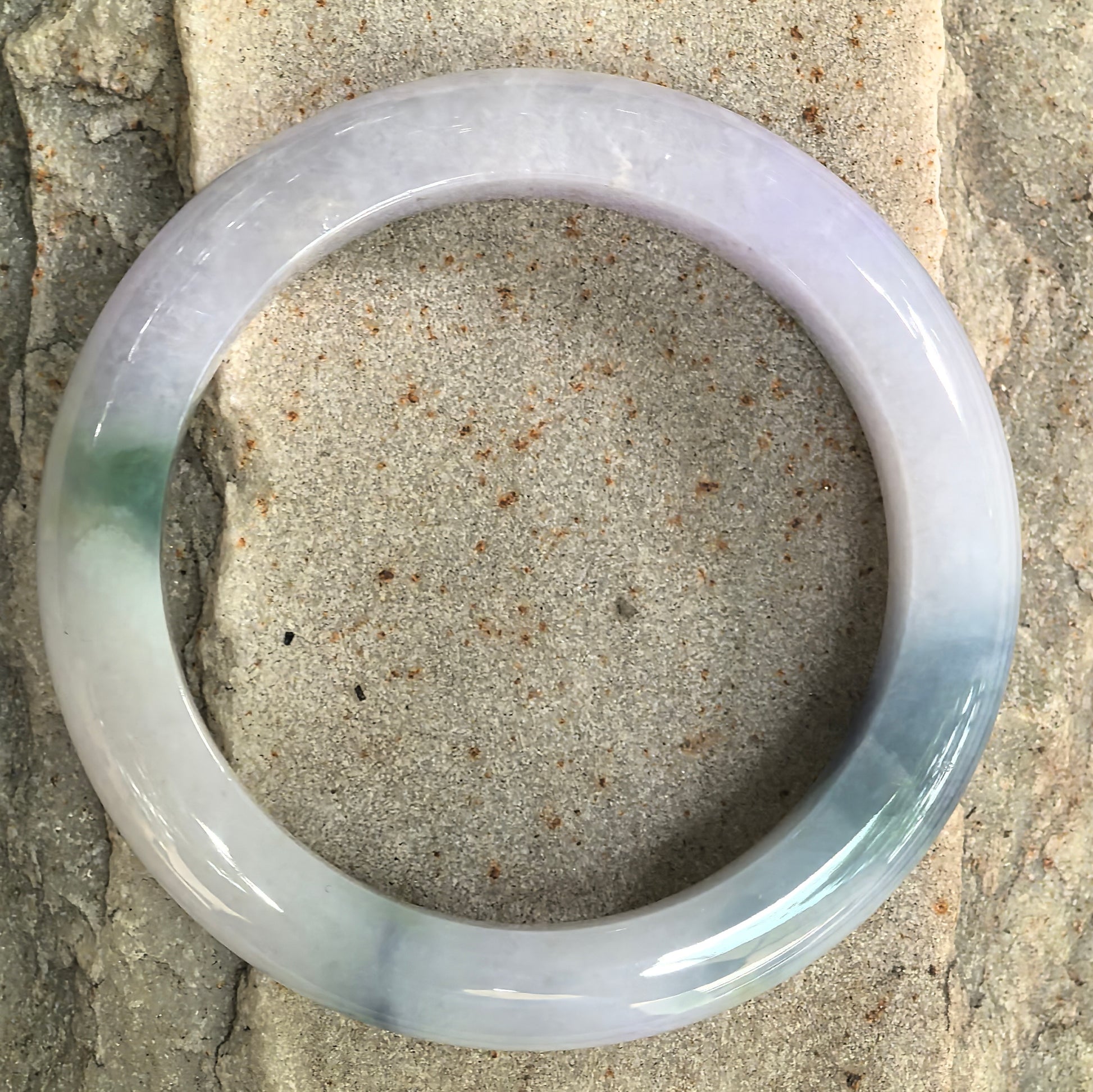 Natural Grade-A jadeite bangle with lavender, pale greenish, and denim blue color zoning.