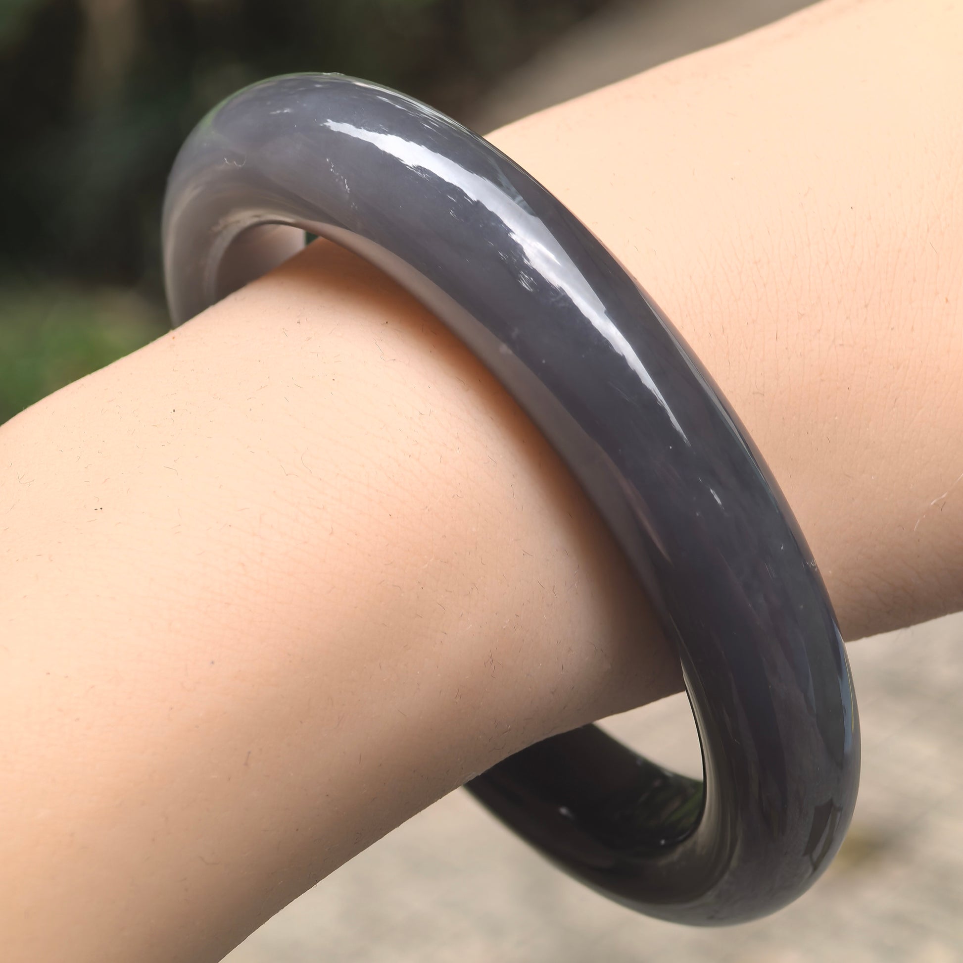 Natural deep smoky purple Hetian jade D-shape bangle worn on wrist.