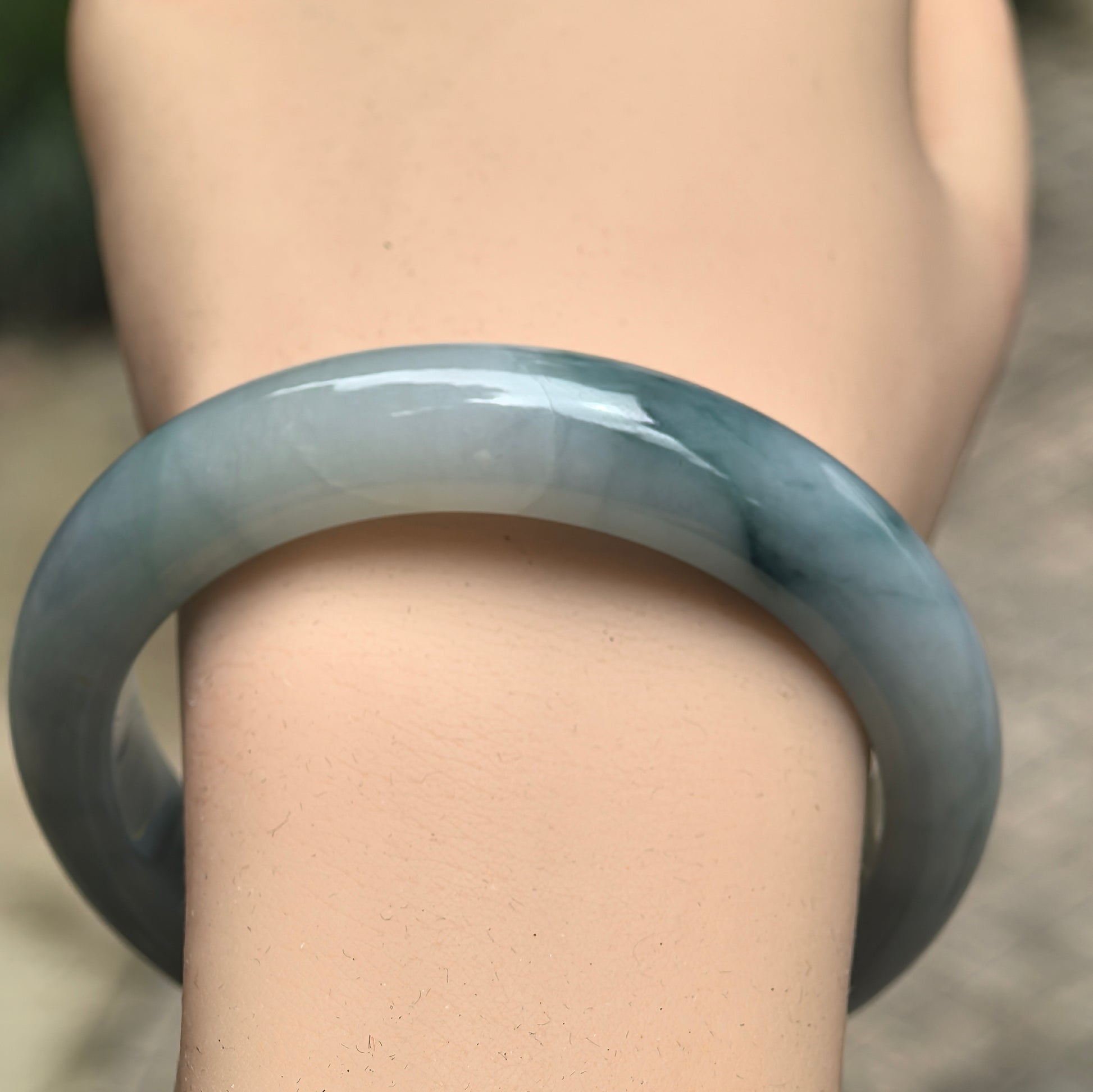 Close-up of glutinous pale green jadeite bangle showing deep green floating color and smooth polish.