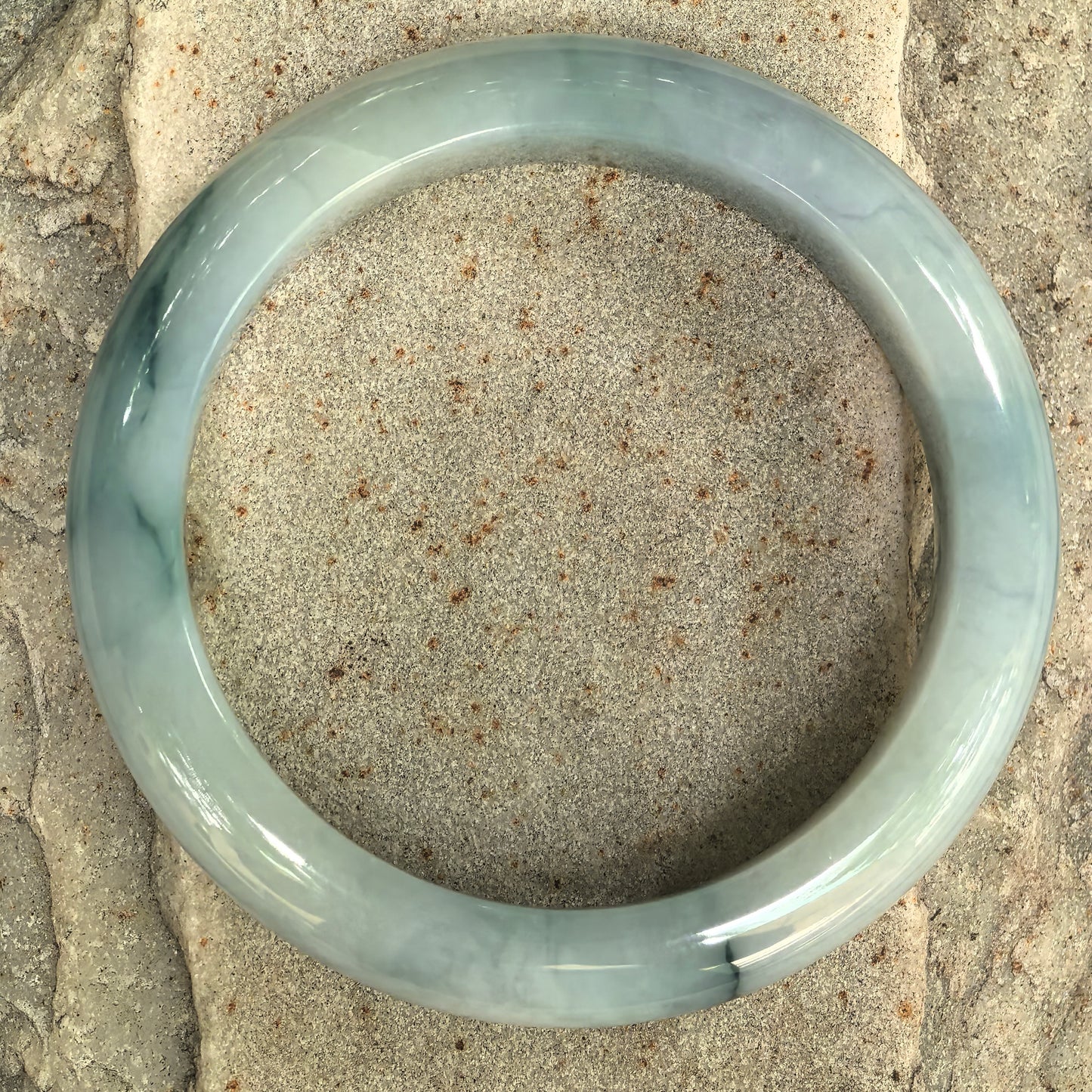 Top view of Natural Grade-A pale green jadeite bangle with dark green floating patterns.