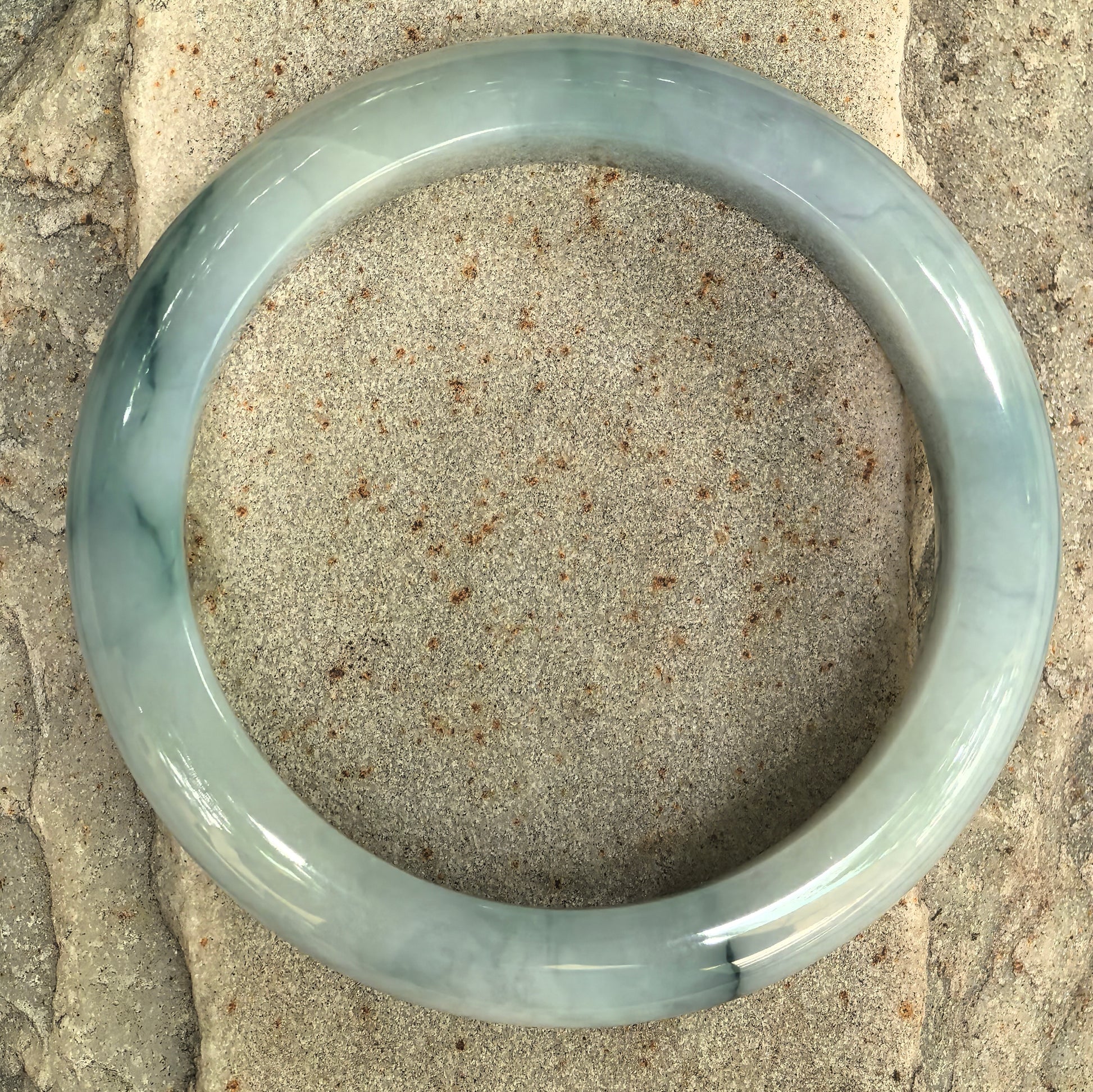 Top view of Natural Grade-A pale green jadeite bangle with dark green floating patterns.