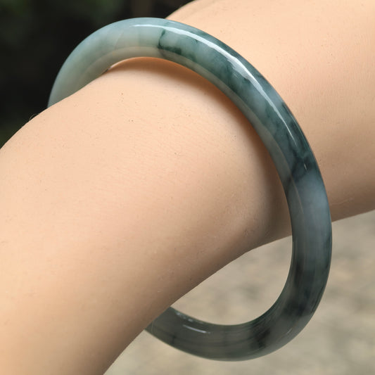 Natural Grade-A glutinous deep green floating flower round-bar jadeite bangle worn on wrist.