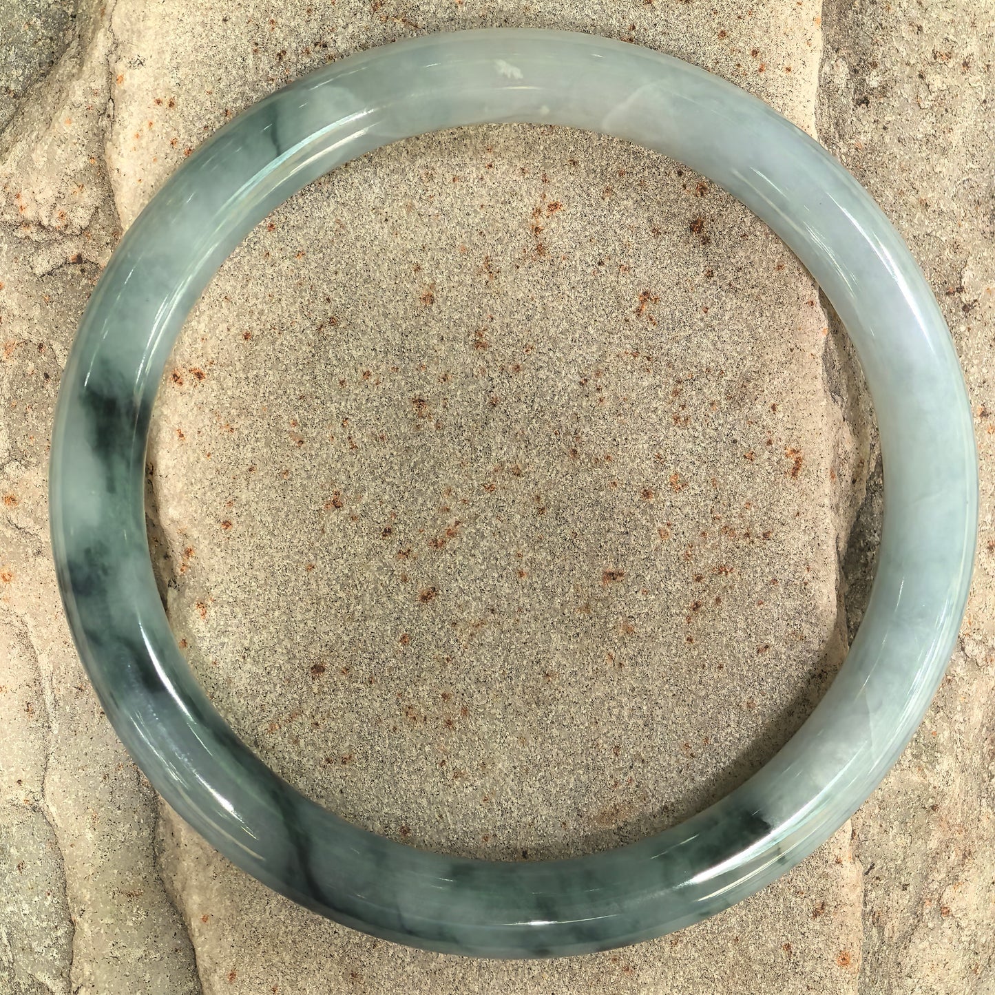 Glutinous jadeite round-bar bangle with pale green base and dark green floating flower pattern.