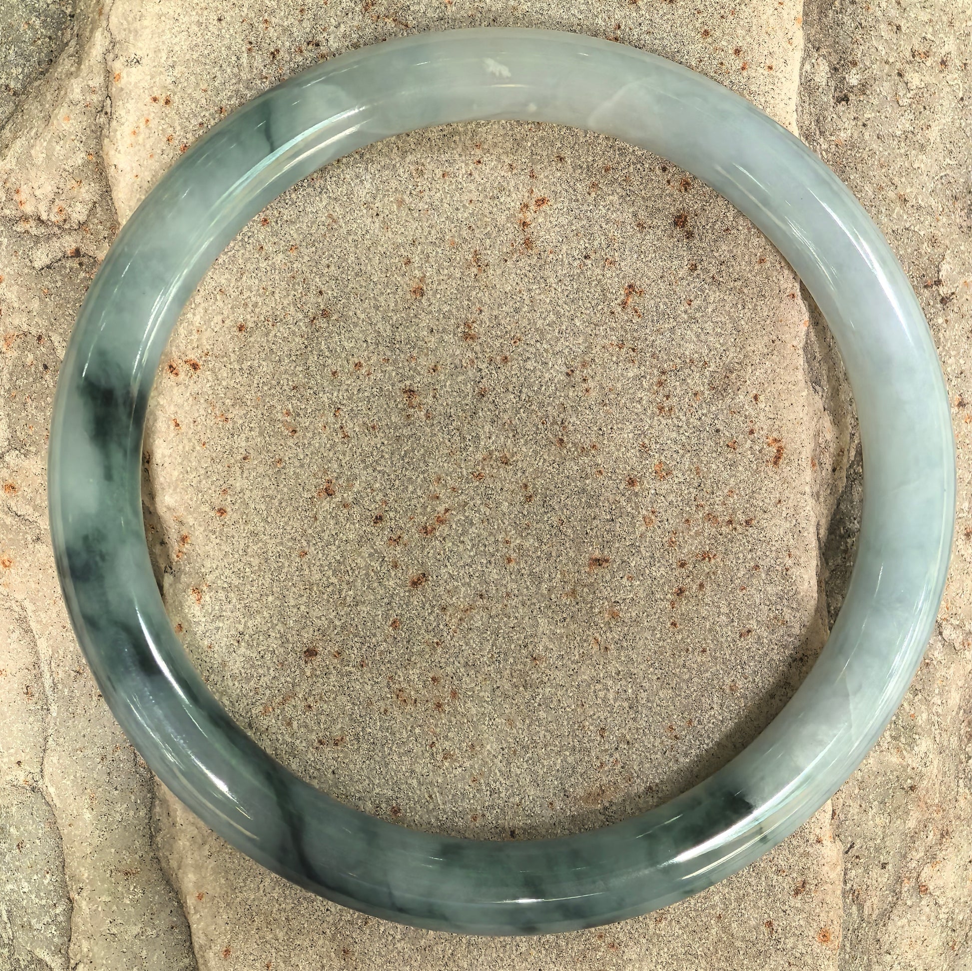 Glutinous jadeite round-bar bangle with pale green base and dark green floating flower pattern.