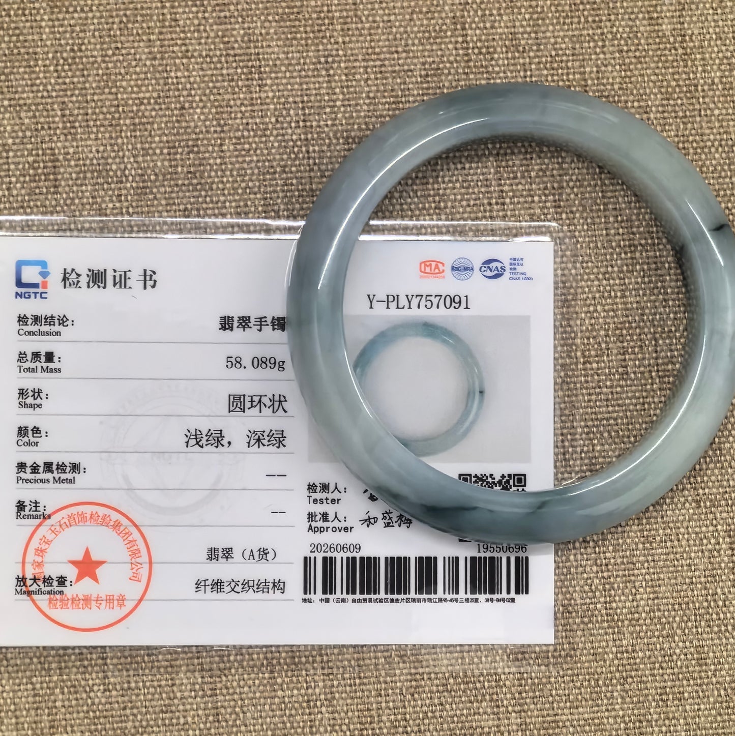 NGTC certified pale green jadeite bangle displayed with its matching certificate.