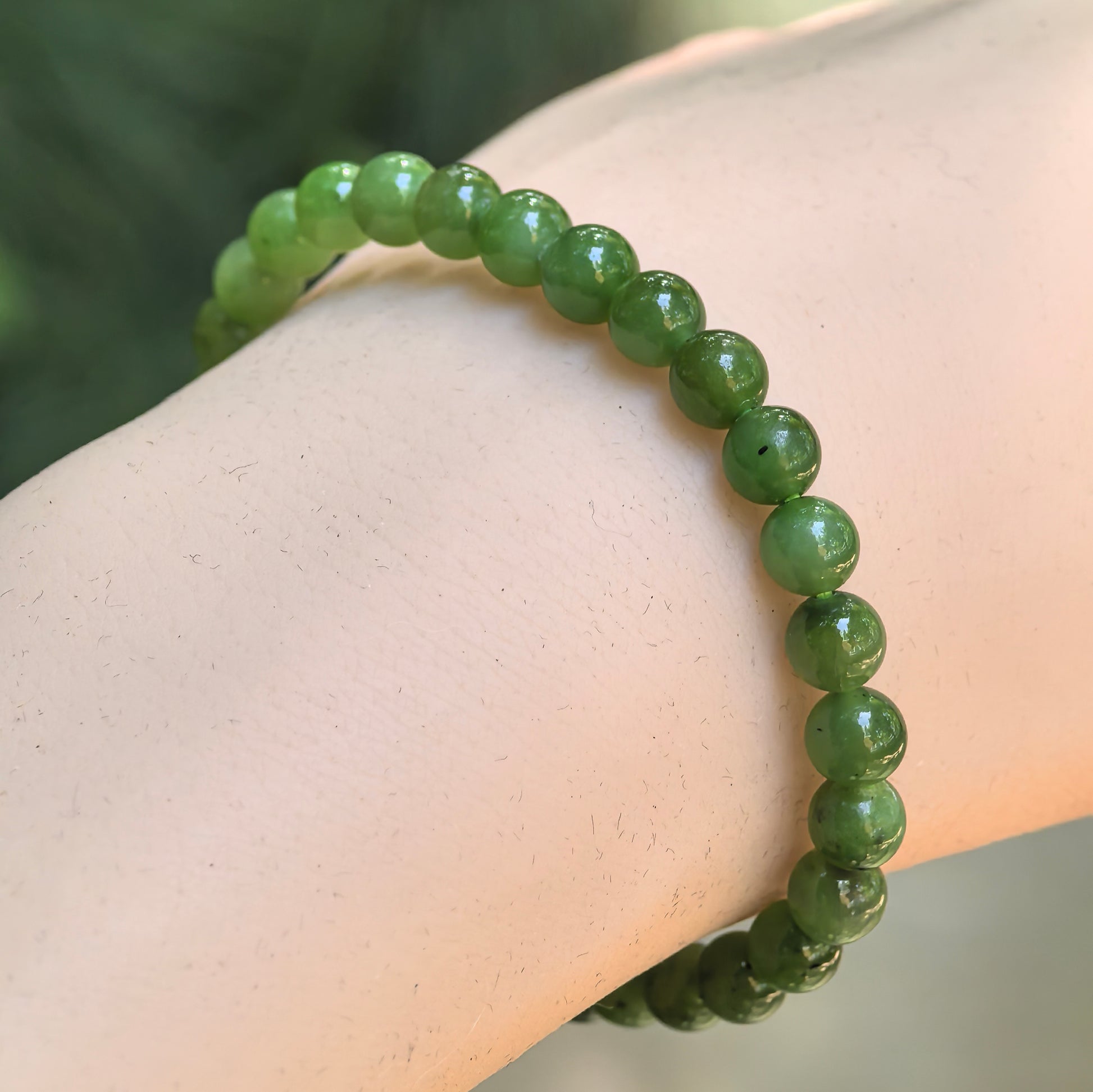 Natural green Hetian jade 6mm bead bracelet worn on wrist.