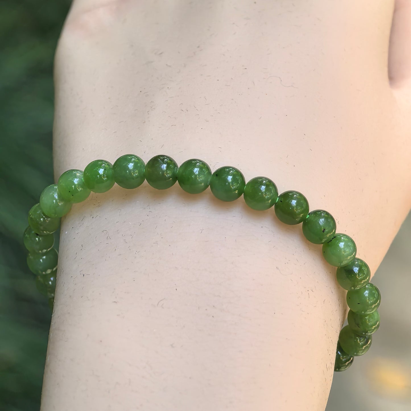 Close-up of green nephrite round bead bracelet with glossy polished surface.