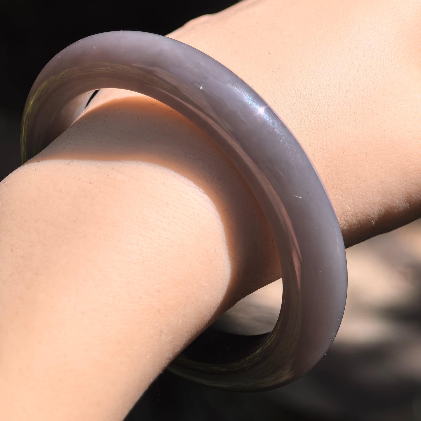 Close-up of glossy smoky purple nephrite bangle showing smooth polished surface.