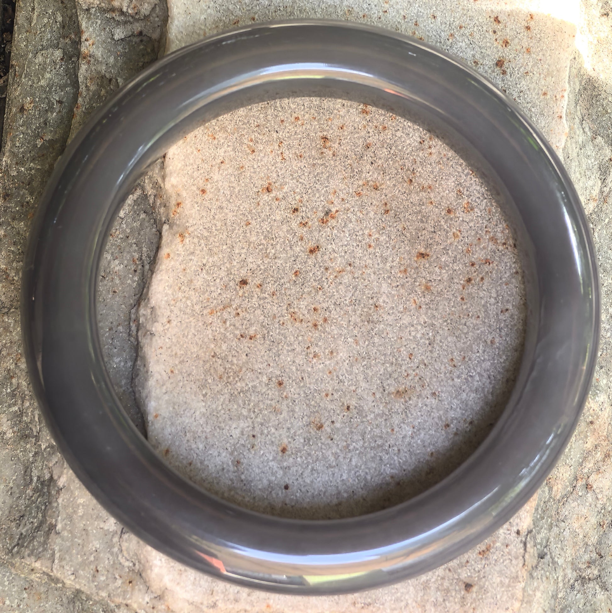 Natural Hetian jade D-shape bangle displayed on stone background with rich gray-purple tone.