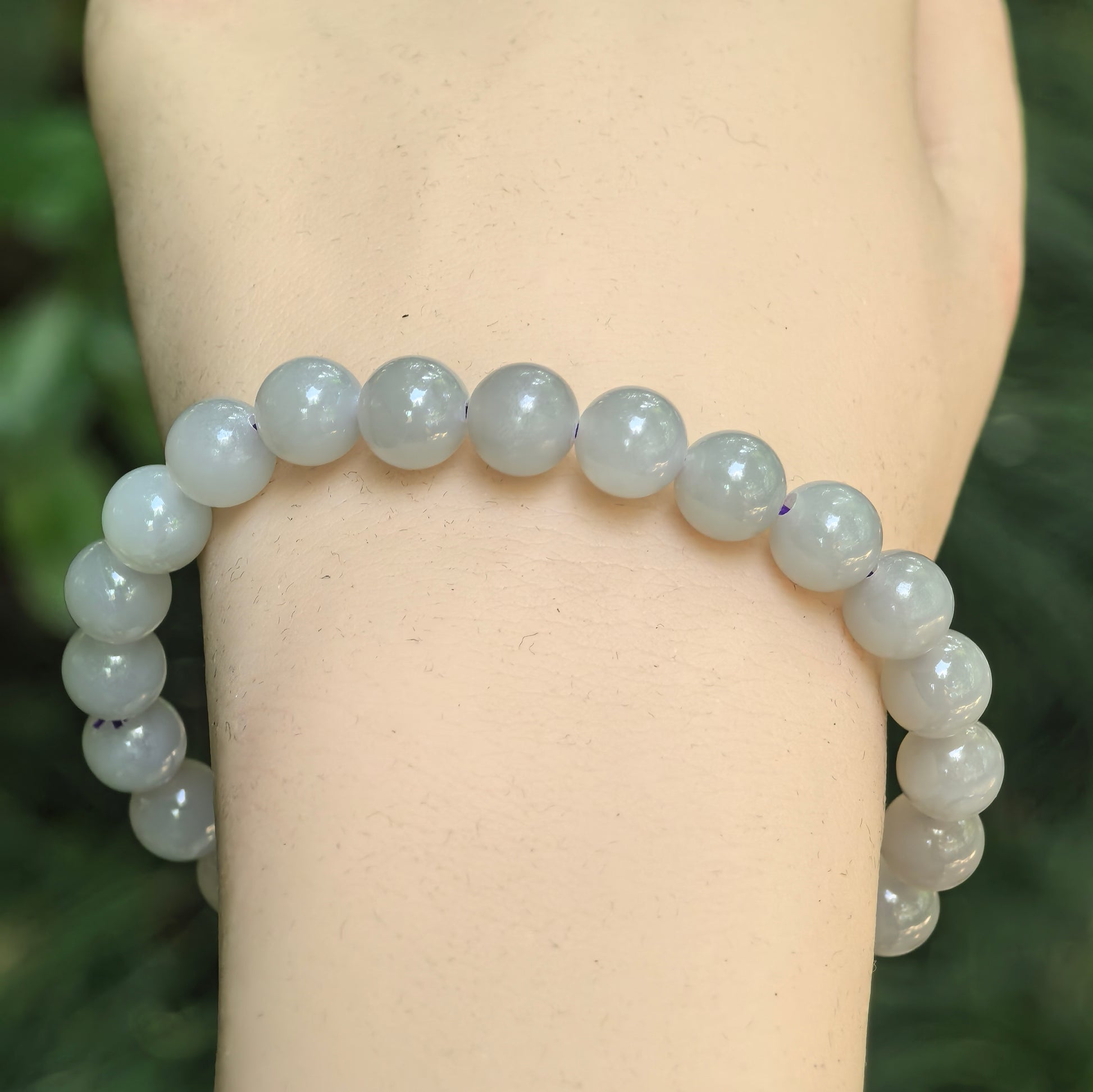 Close-up of gray-purple nephrite round bead bracelet with glossy polished surface.