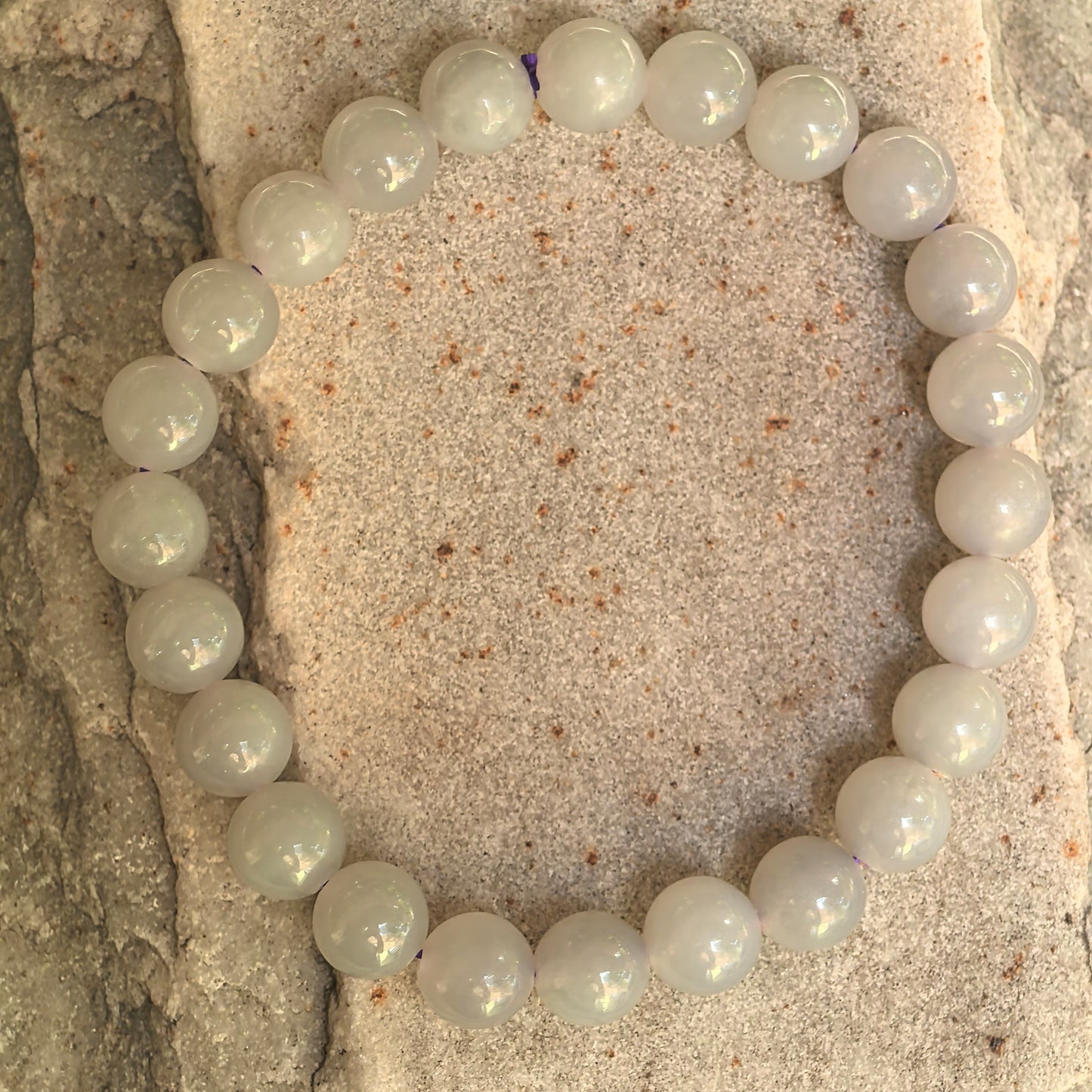 Natural Hetian jade bracelet with 23 round gray-purple beads displayed on stone background.
