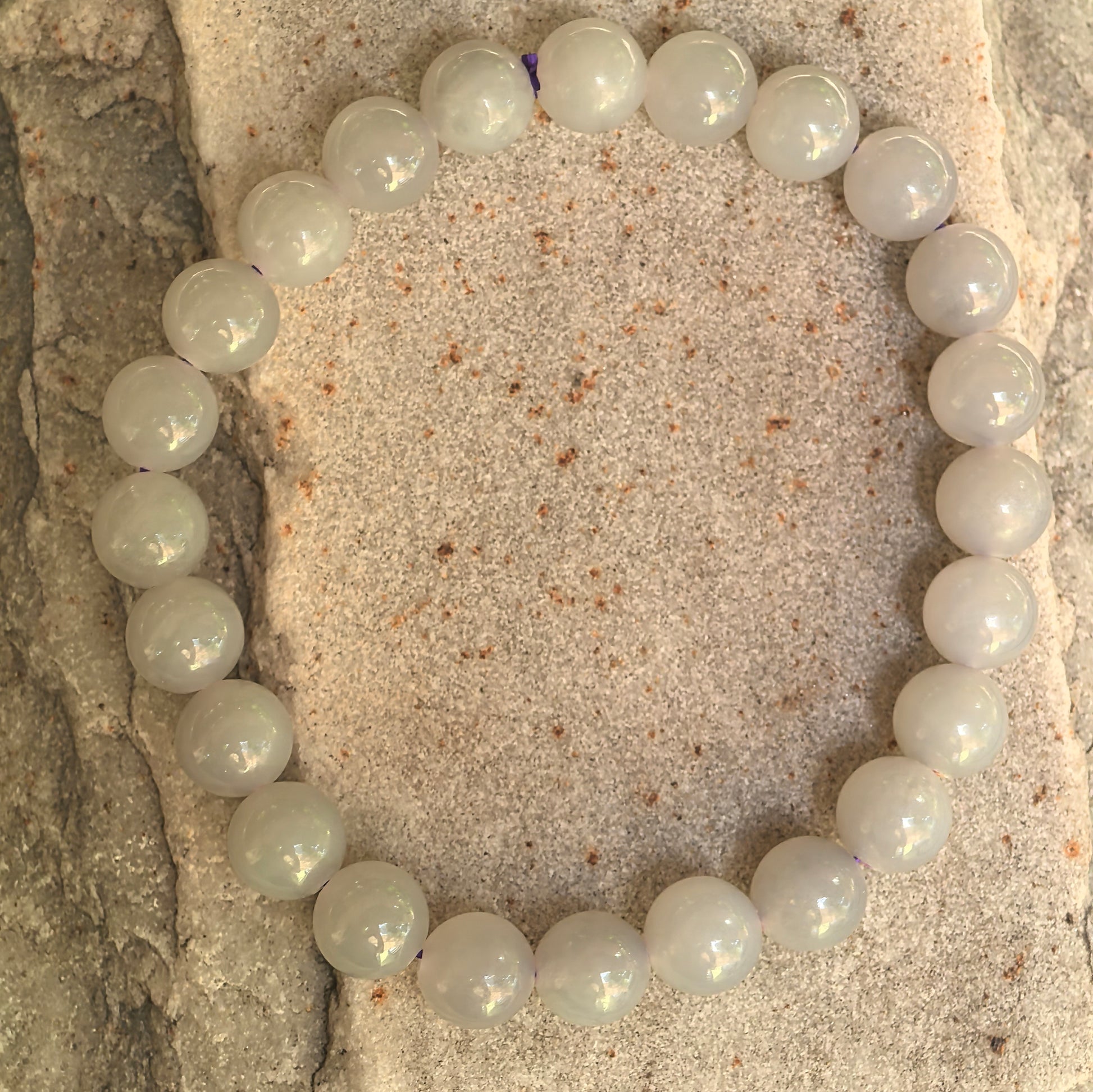 Natural Hetian jade bracelet with 23 round gray-purple beads displayed on stone background.