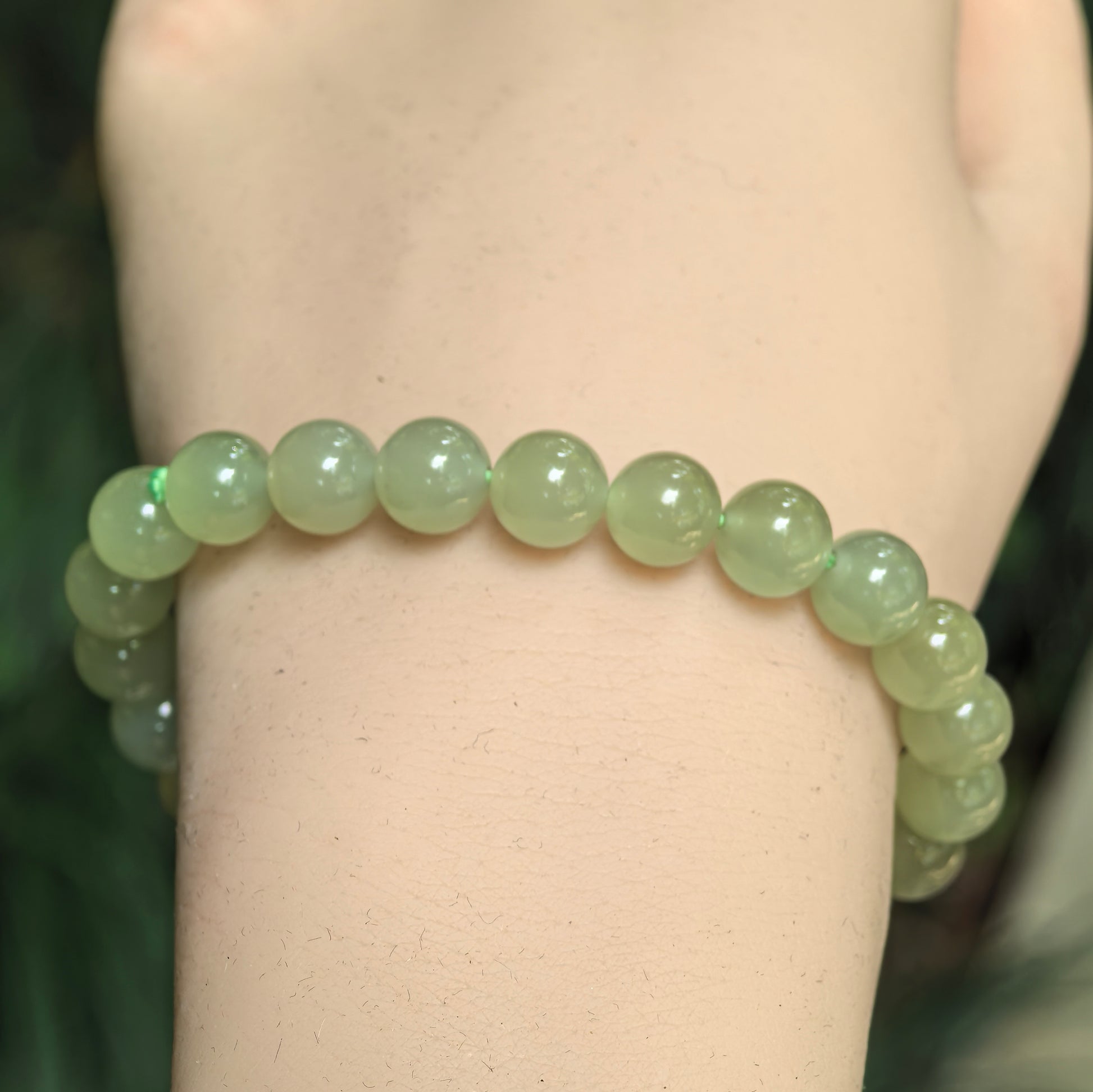 Close-up of green nephrite round bead bracelet with glossy polished surface.