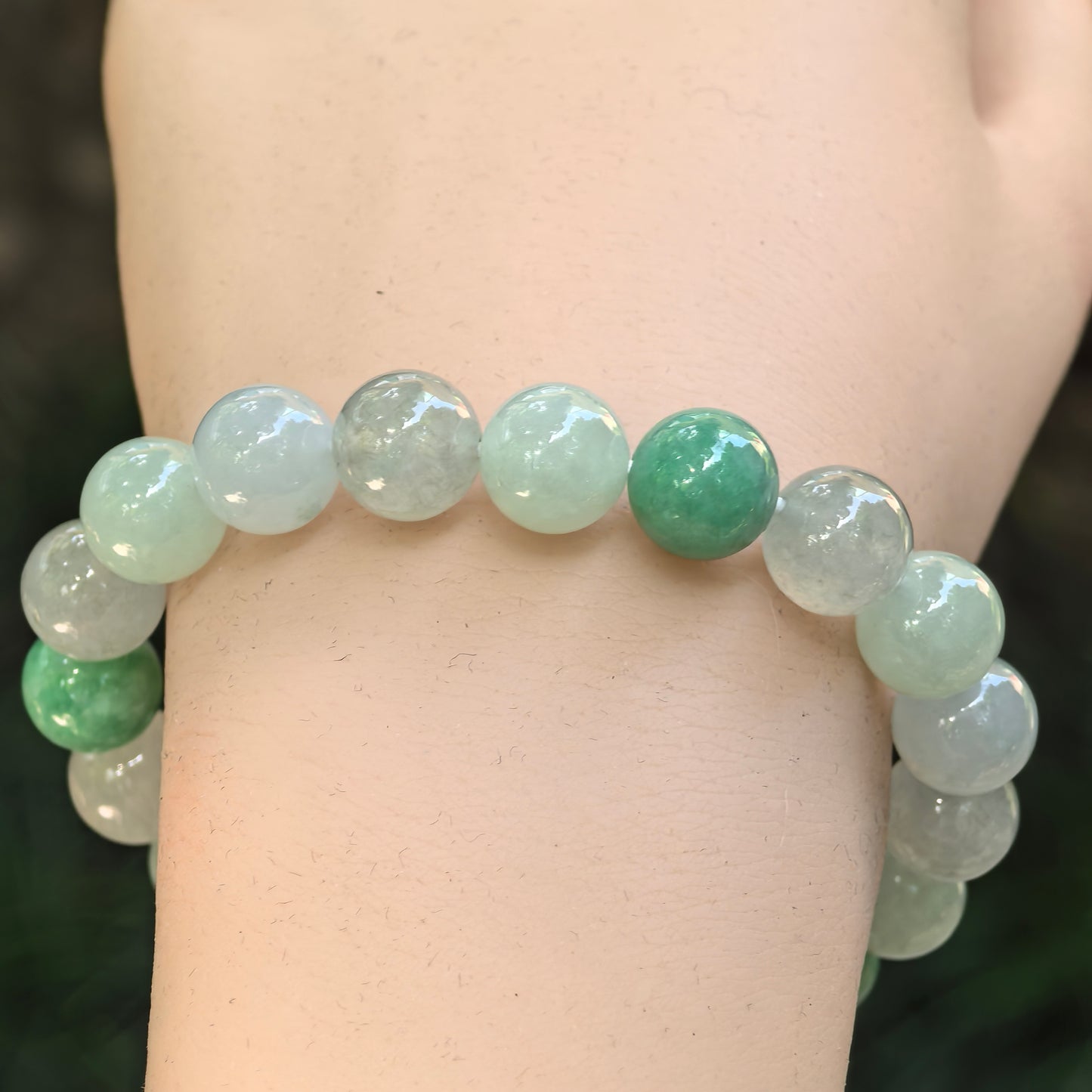 Close-up of light green jadeite bead bracelet with deeper green accent beads.