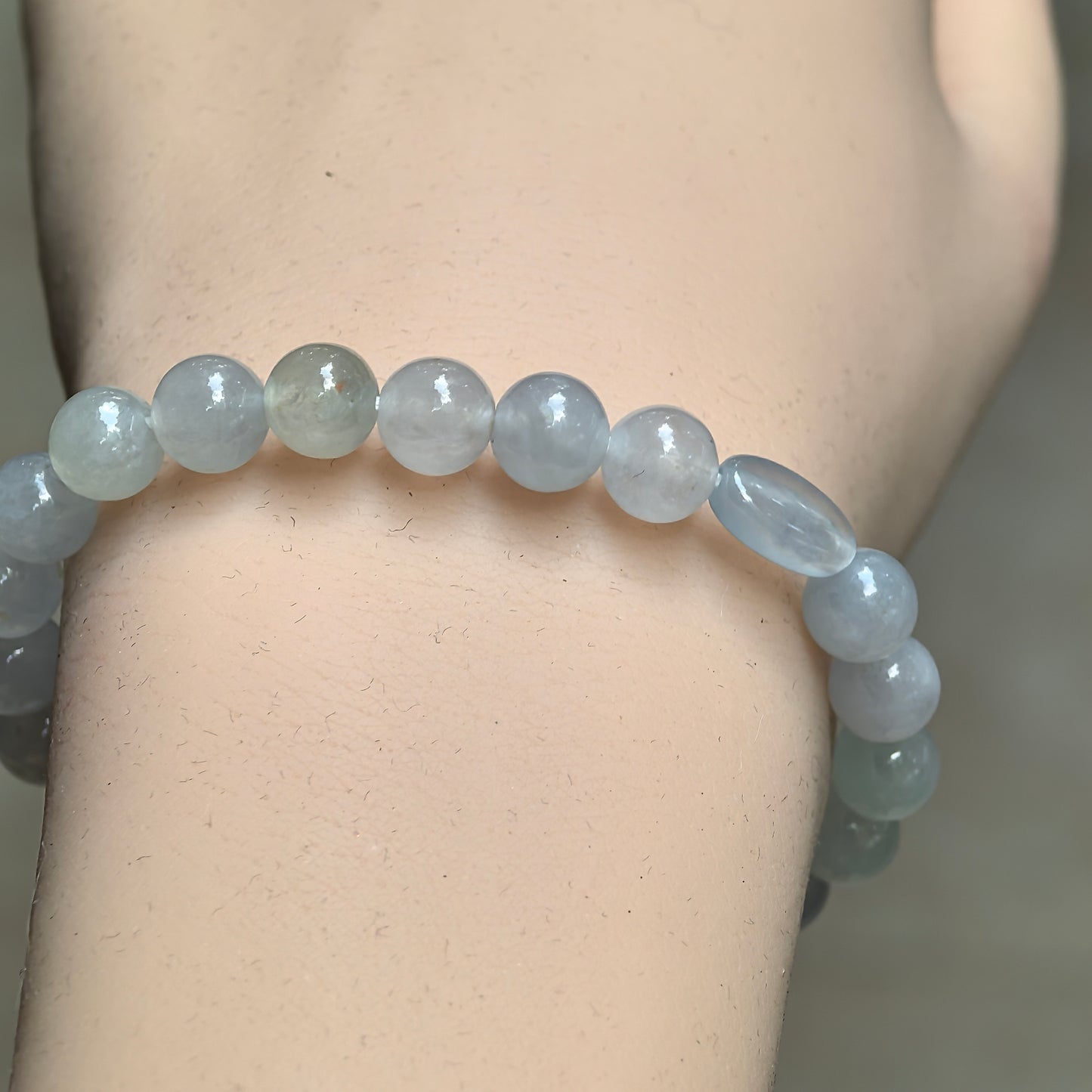Close-up of white jadeite bead bracelet with pale green and light gray tones.