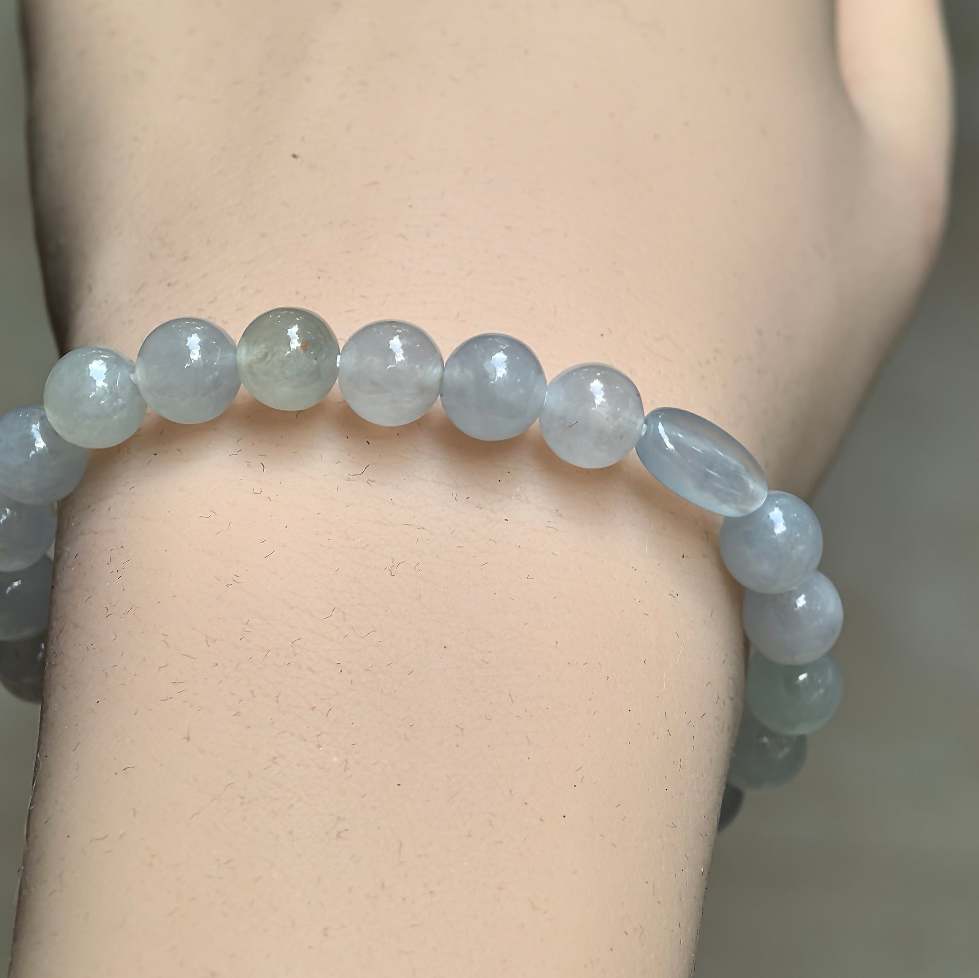 Close-up of white jadeite bead bracelet with pale green and light gray tones.