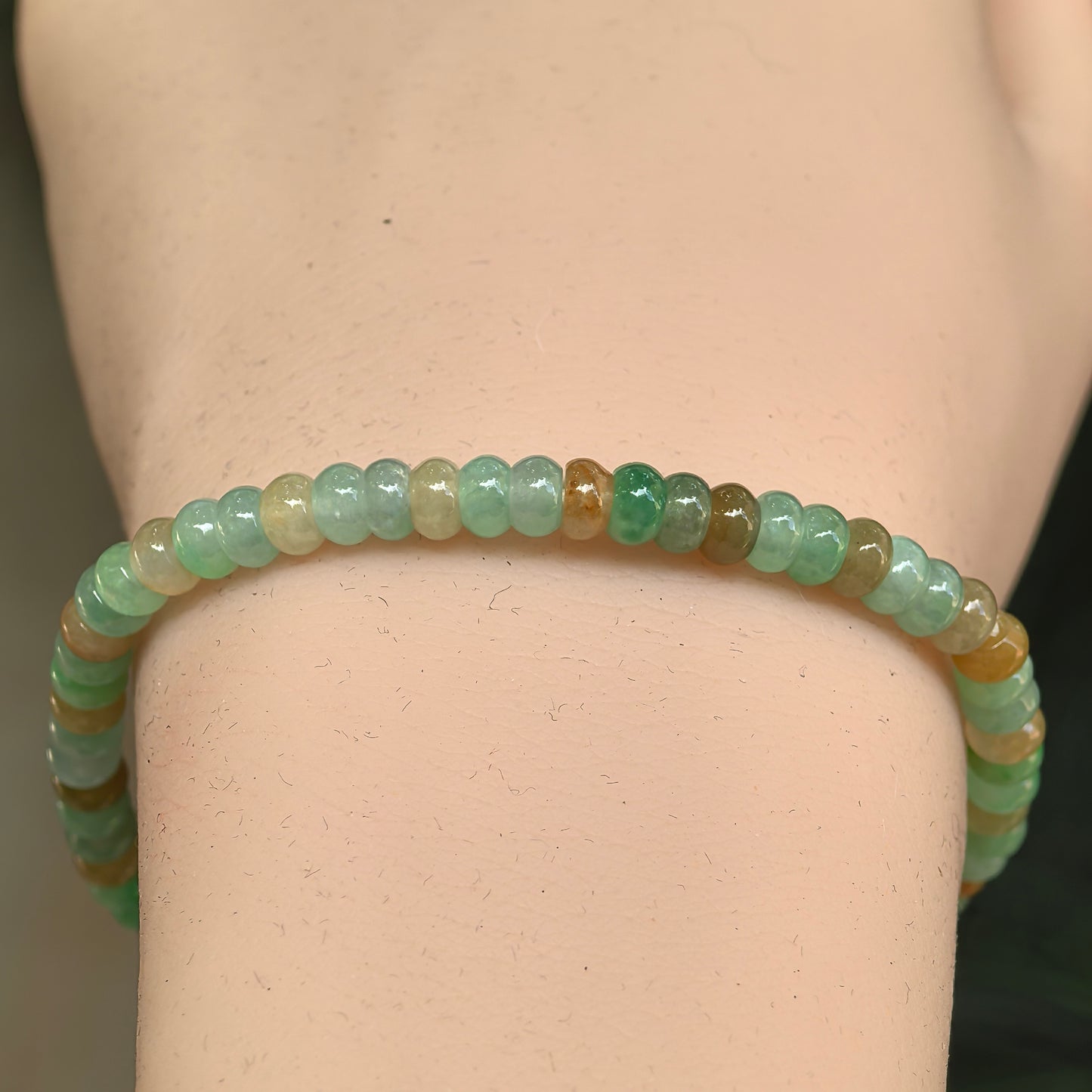 Close-up of multicolor jadeite abacus bead bracelet with green, yellow, and honey tones.