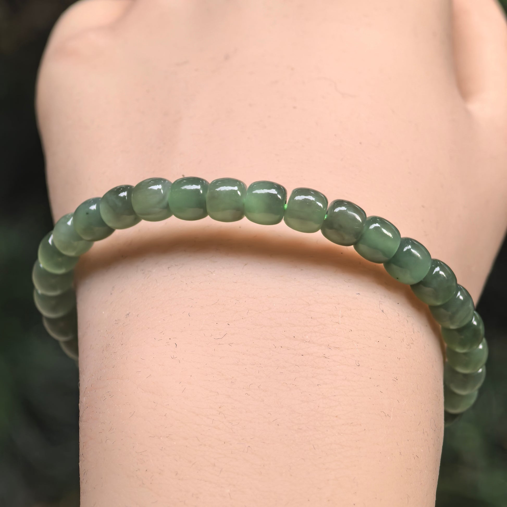 Close-up of green nephrite abacus bead bracelet with glossy polished surface.