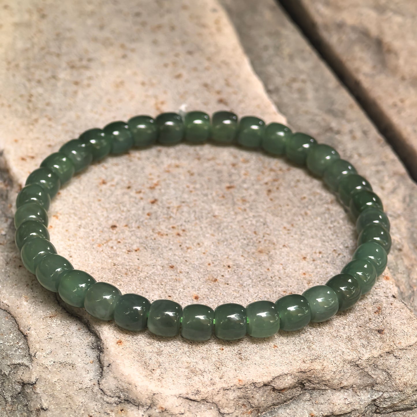 Green nephrite elastic bead bracelet showing natural tonal variation.