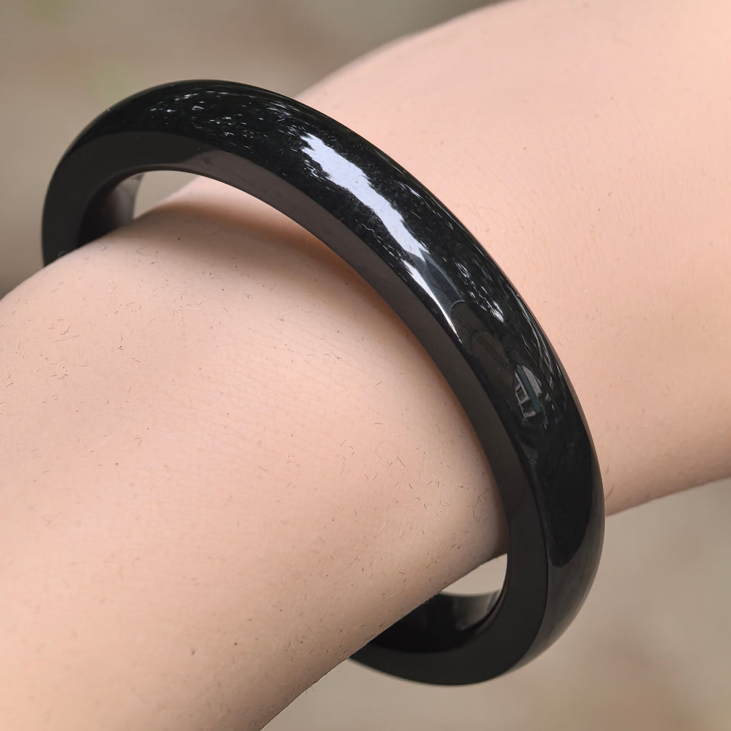Natural deep green Hetian jade square bangle worn on the wrist with glossy polished surface.