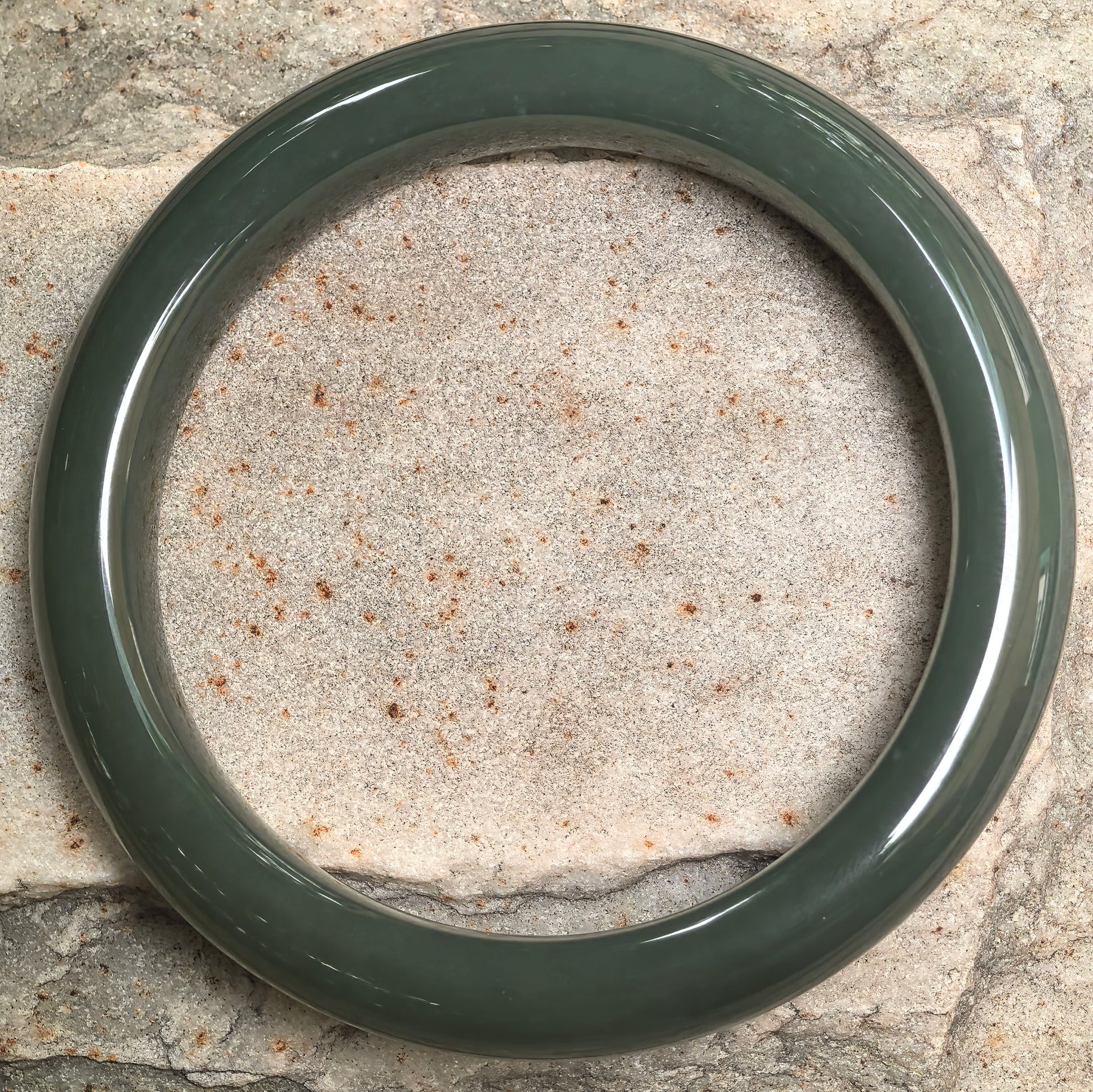 Top view of deep green Hetian jade bangle showing classic circular shape and even polish.