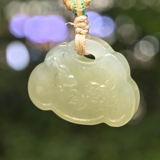 Natural light green Hetian jade lotus fish pendant hanging with woven cord.