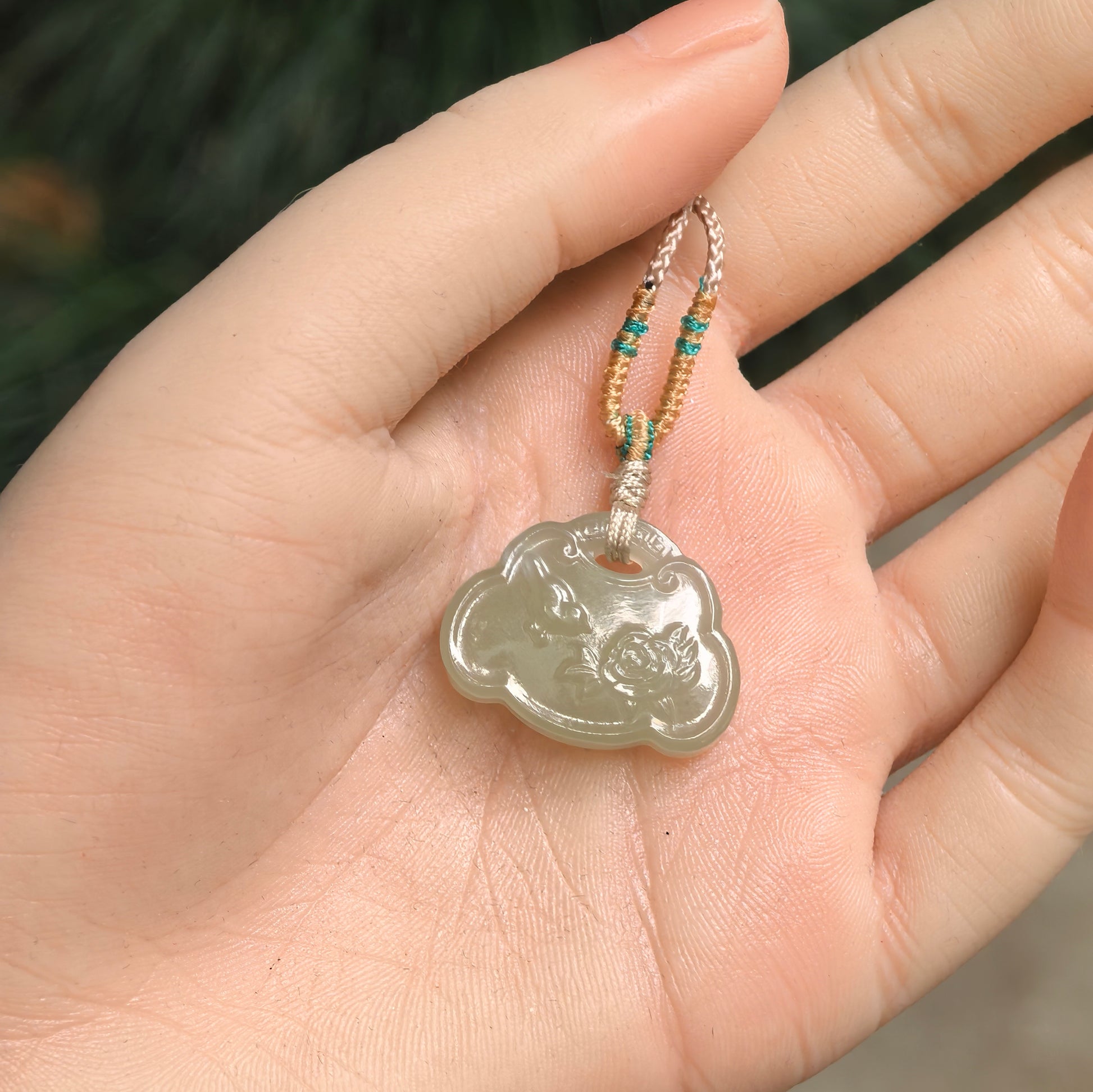 Natural Hetian jade lotus fish pendant displayed on hand with soft polished luster.