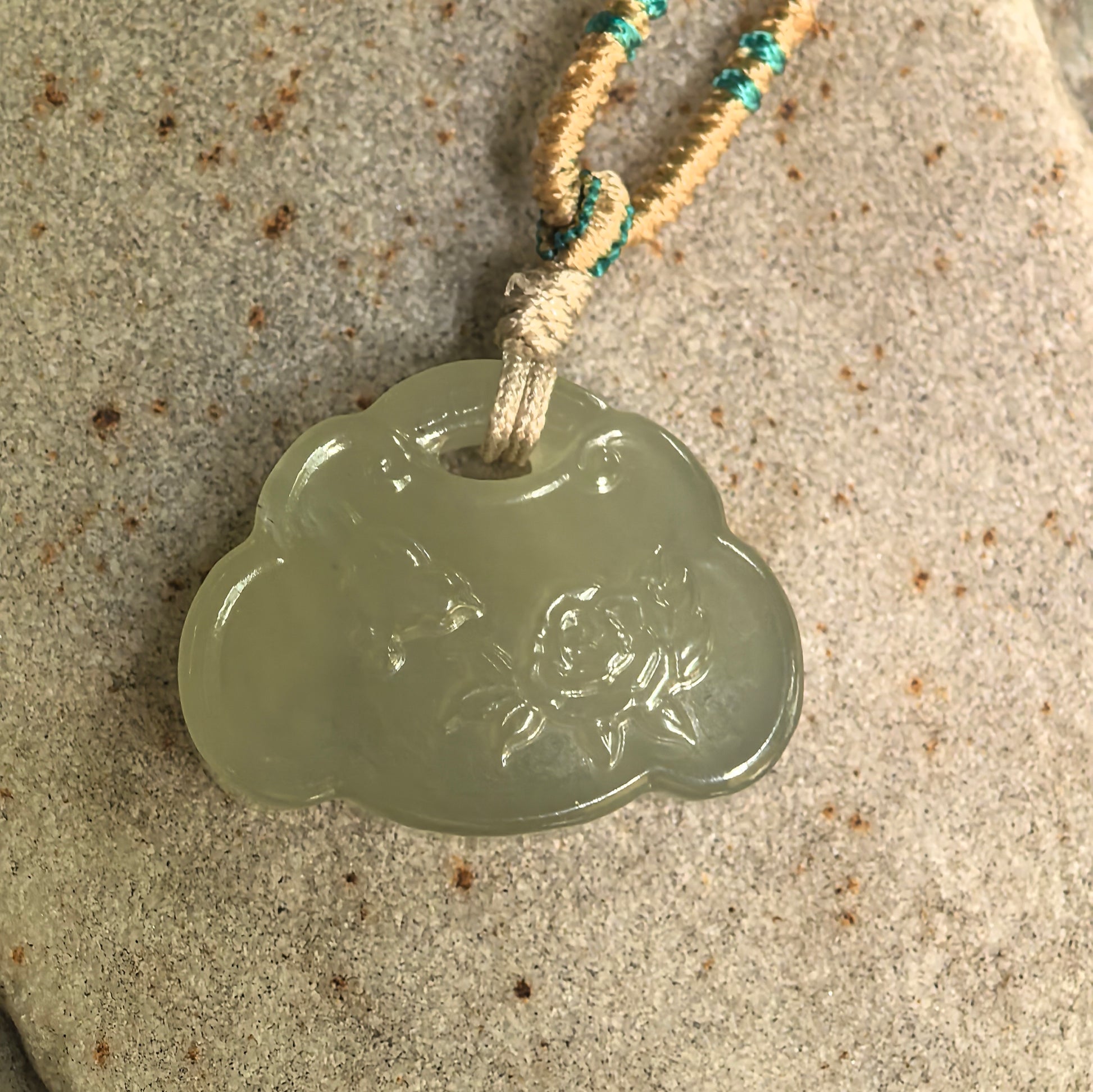 Natural Hetian jade lotus fish pendant displayed on hand with soft polished luster.