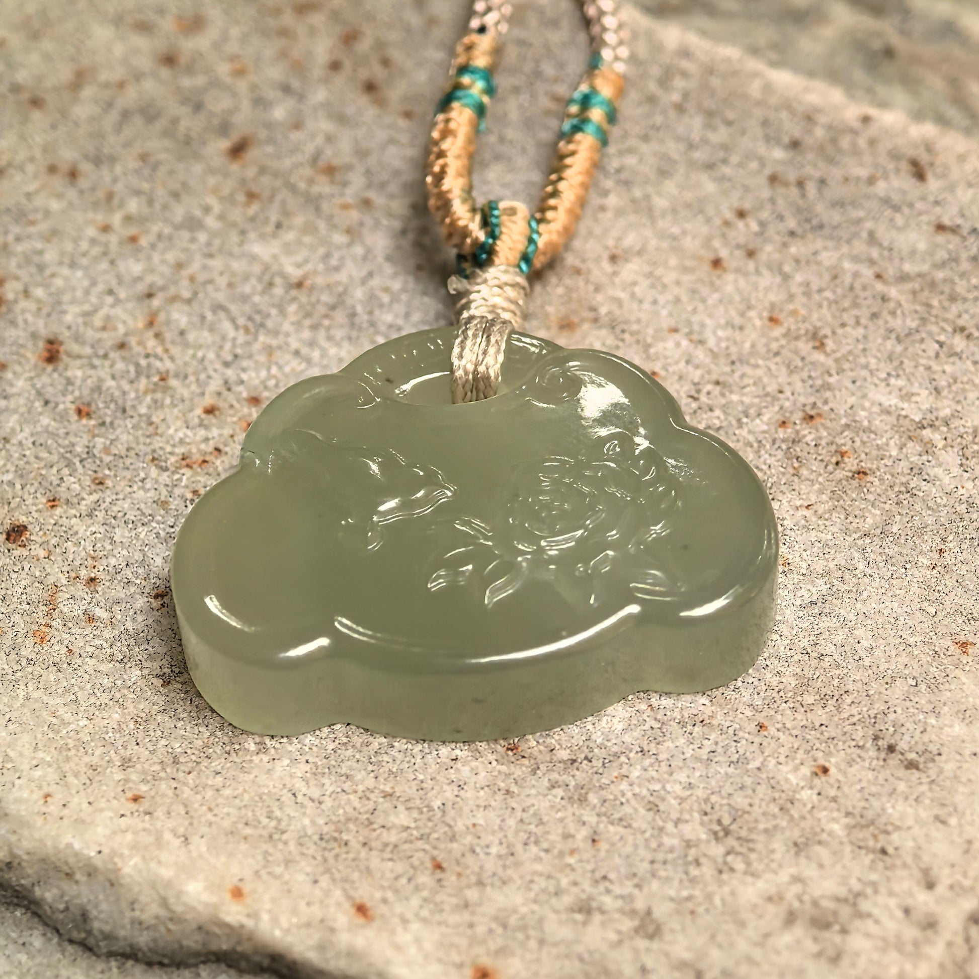 Side view of light green Hetian jade carved pendant showing compact thickness.