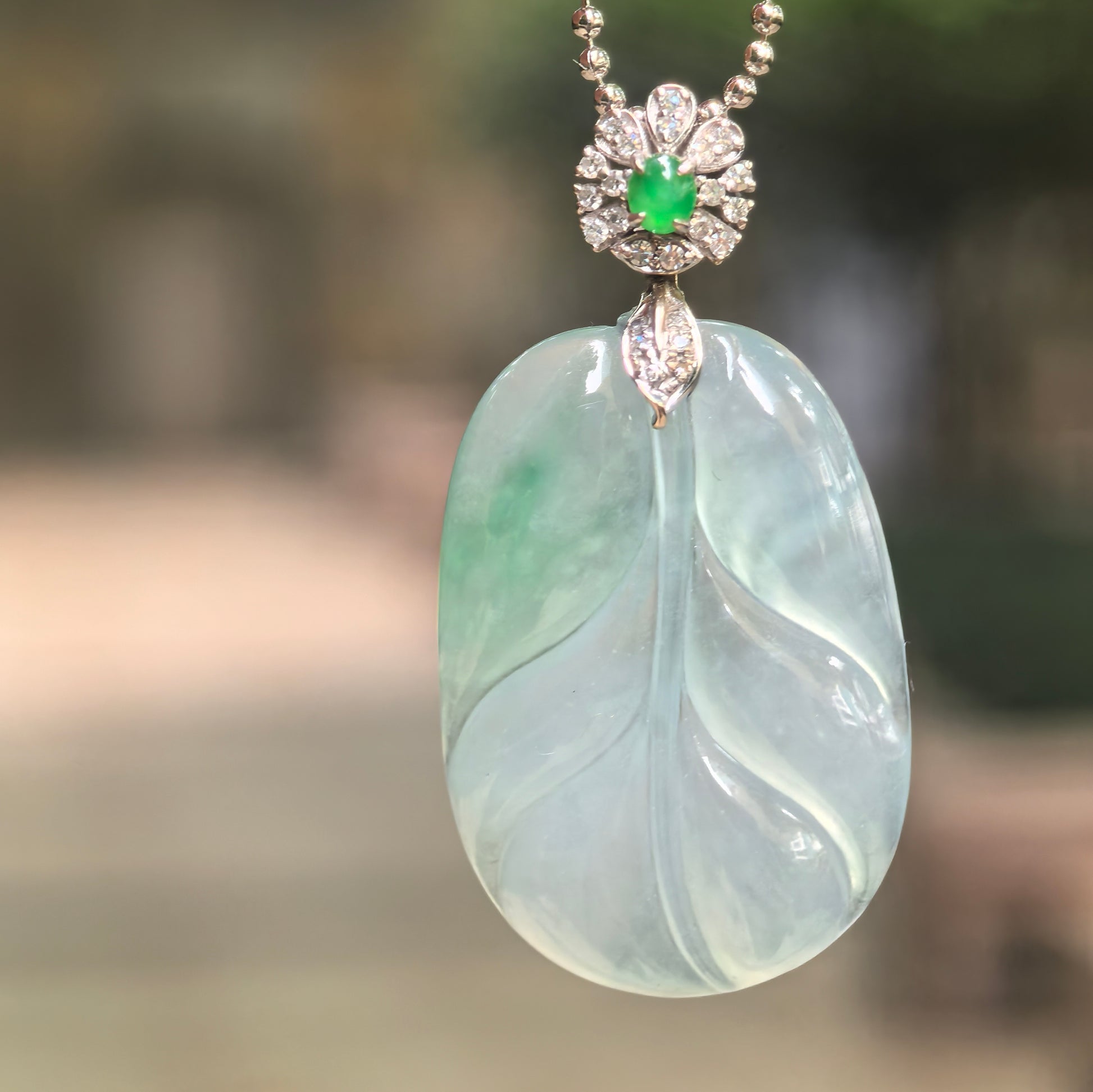Natural Grade-A icy glutinous light green jadeite leaf pendant with 18K gold diamond setting showing translucent texture and fine leaf carving detail.
