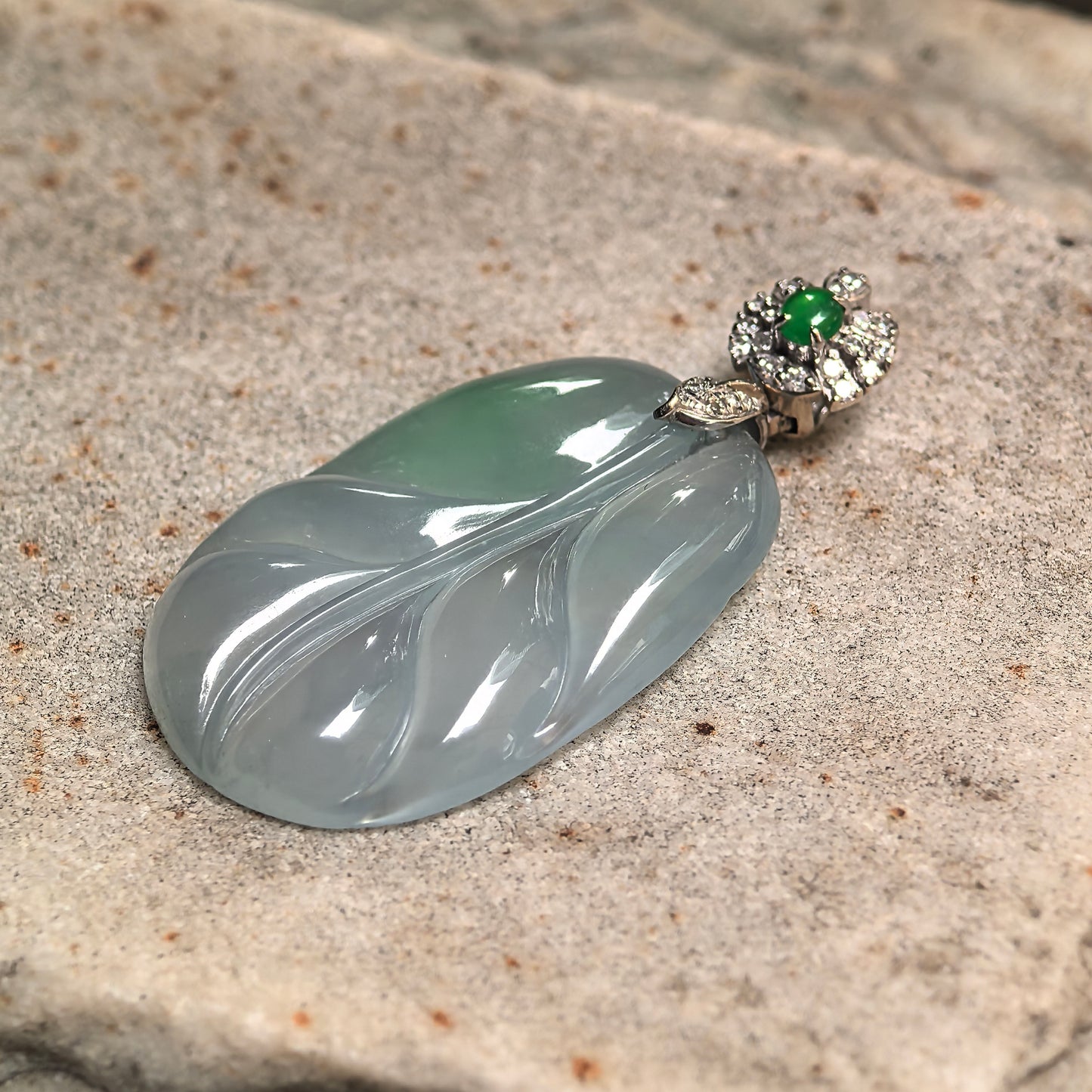 18K gold diamond-set jadeite leaf pendant photographed at angle emphasizing carving depth, metal contrast, and jade translucency.