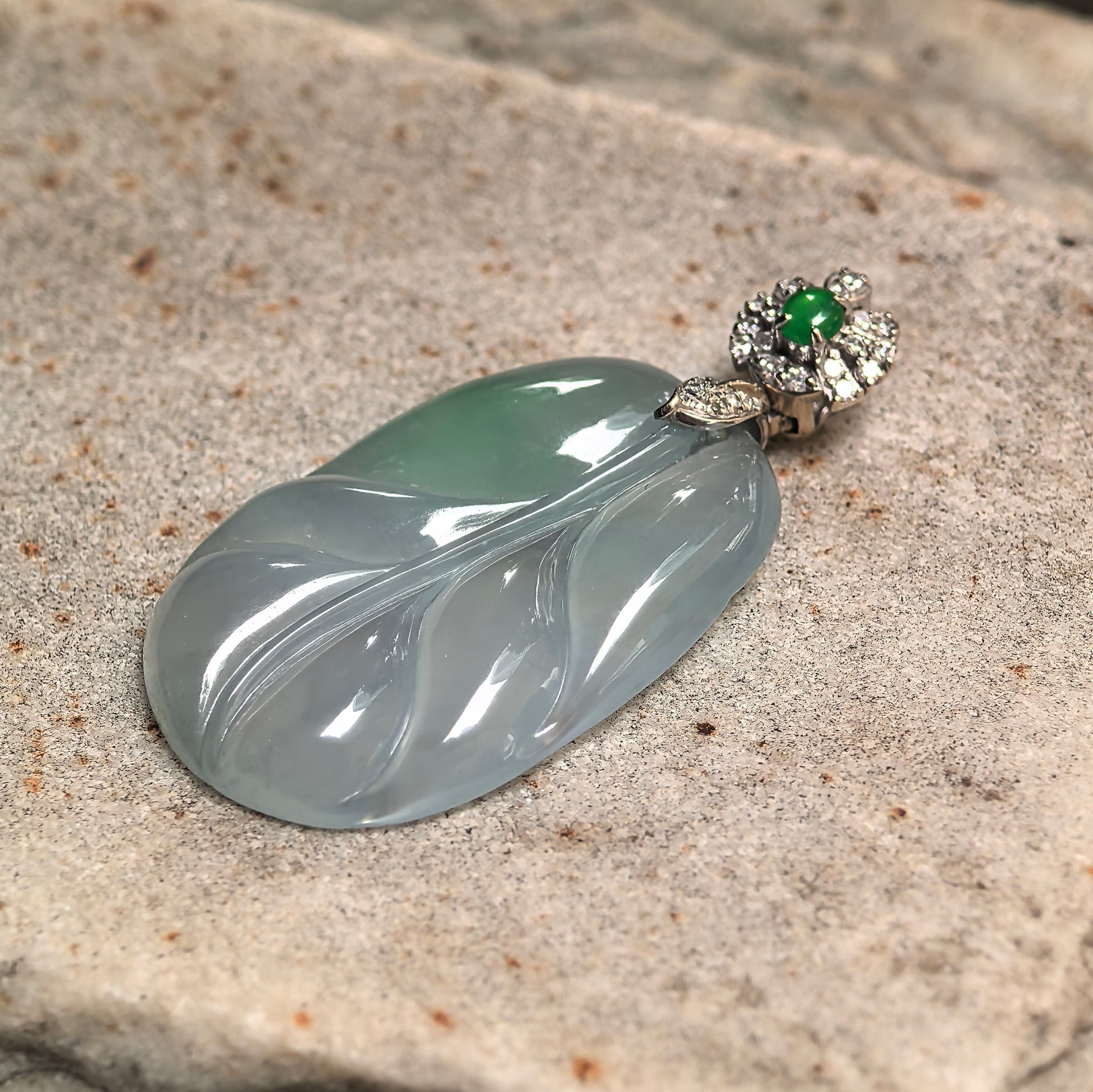 18K gold diamond-set jadeite leaf pendant photographed at angle emphasizing carving depth, metal contrast, and jade translucency.