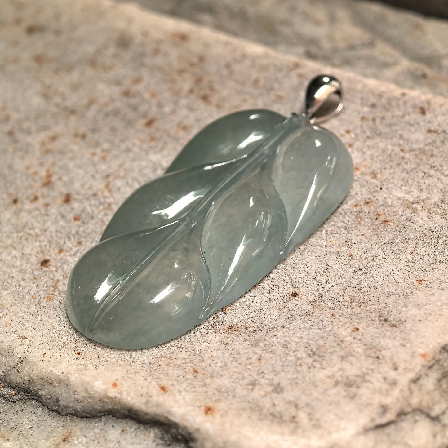 Detail view of leaf carving veins and natural jade internal structure with smooth reflective luster.