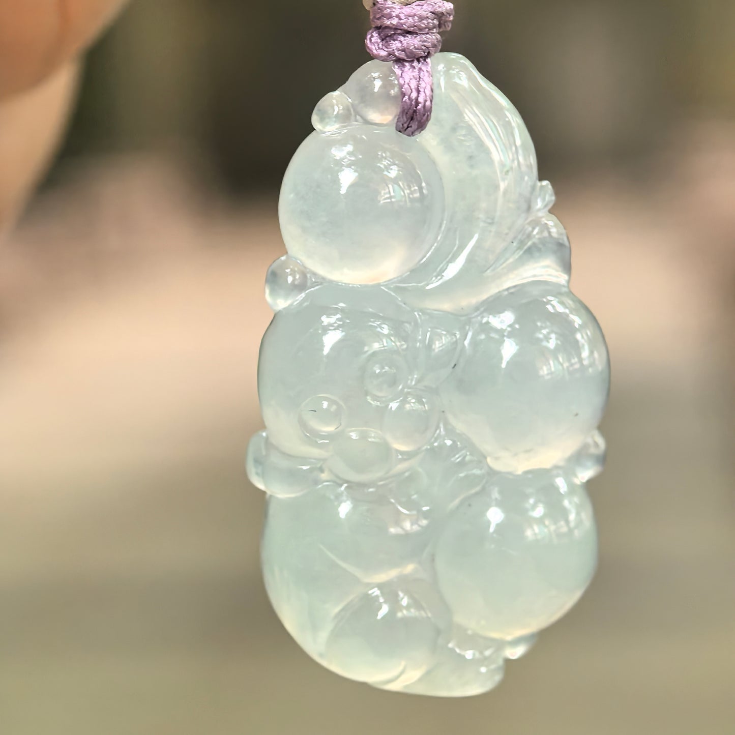 Natural Grade-A glutinous icy pale green monkey jadeite pendant hanging on cord.