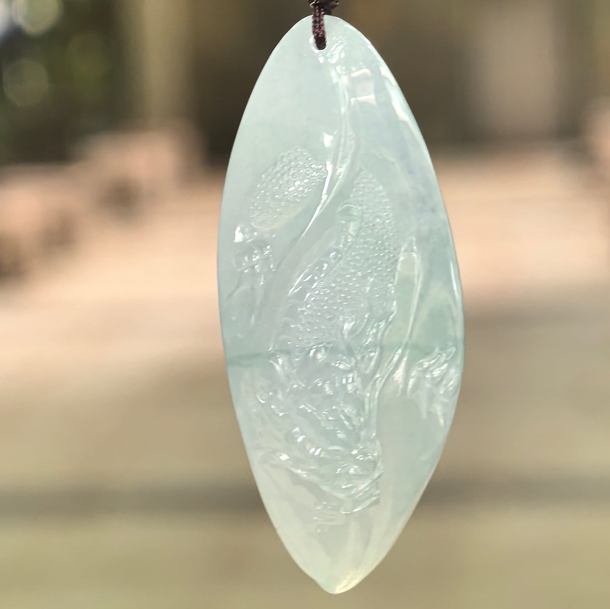 Natural Grade-A icy glutinous light green dragon jadeite pendant hanging on cord with soft translucent texture.