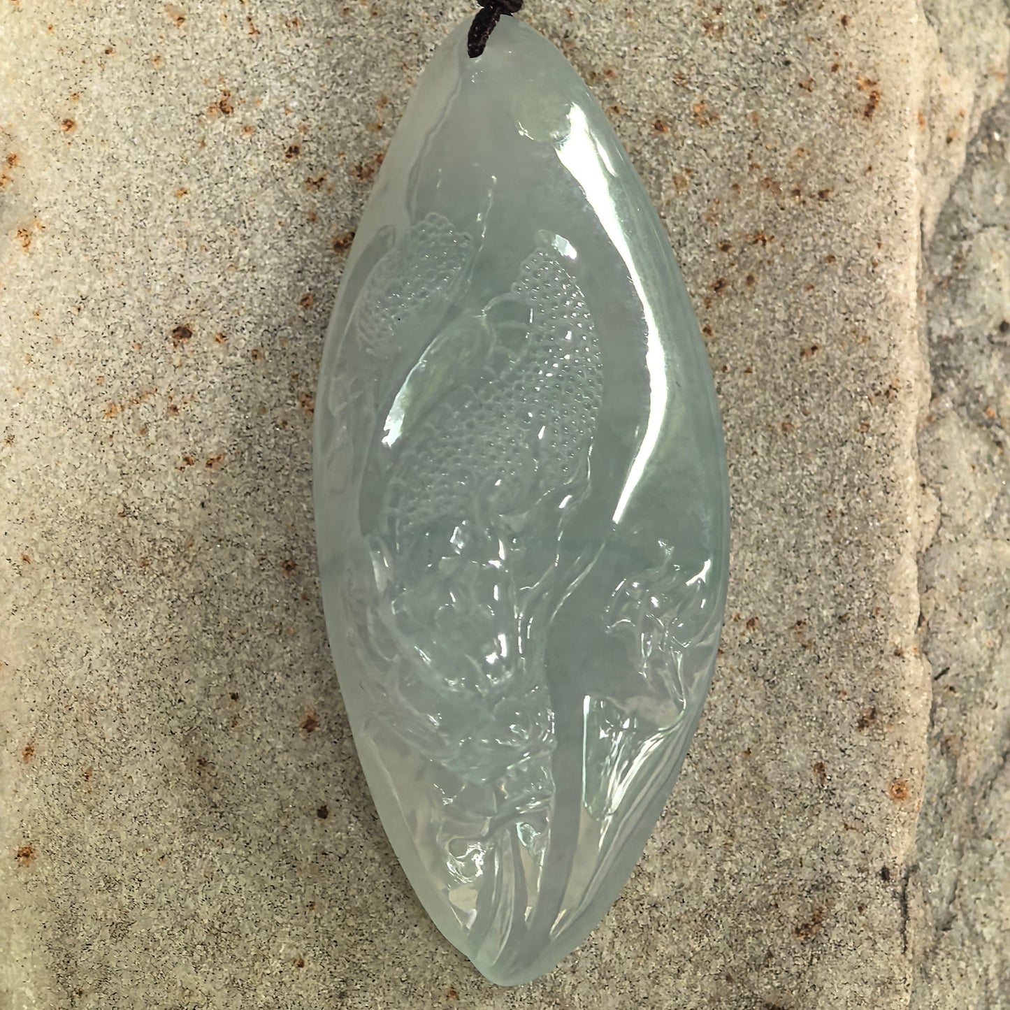 Close-up of light green jadeite dragon pendant showing fine carving details and icy-gel surface.