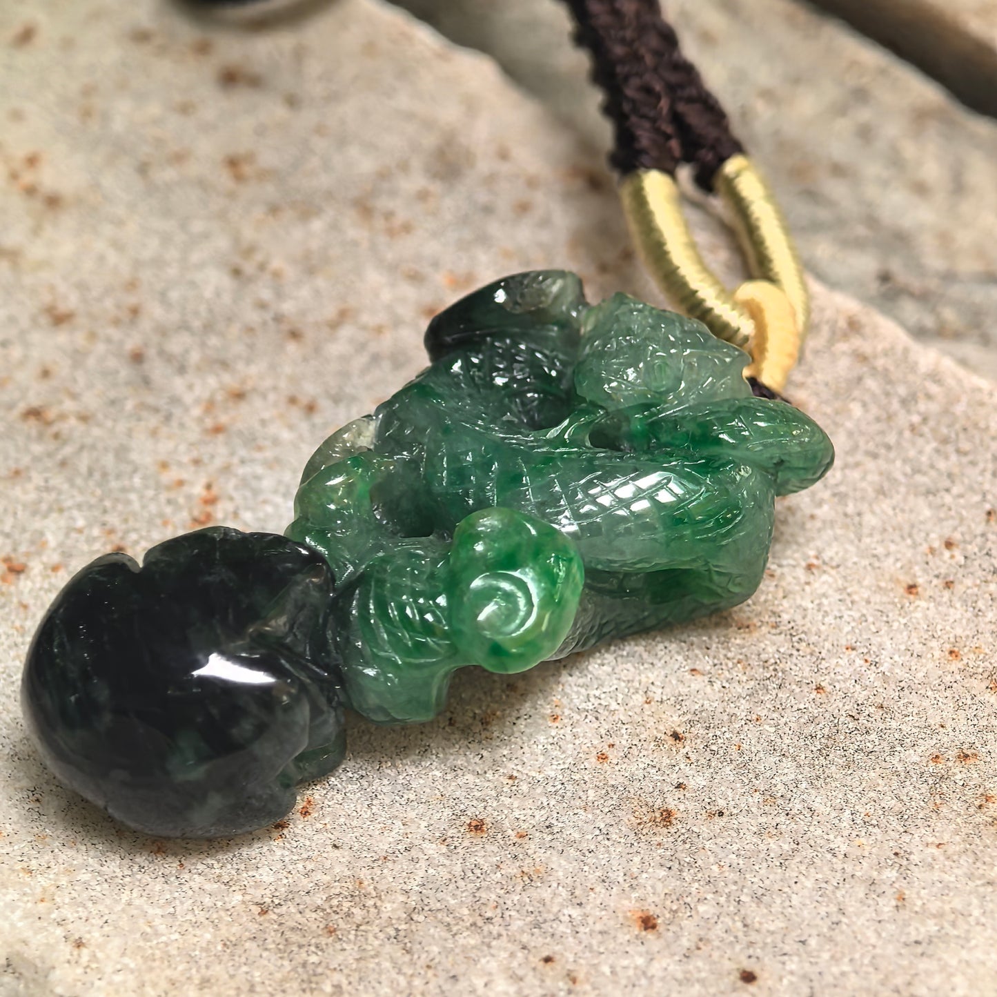 Side view of natural jadeite snake pendant showing thick 3D carving and dark mineral area.