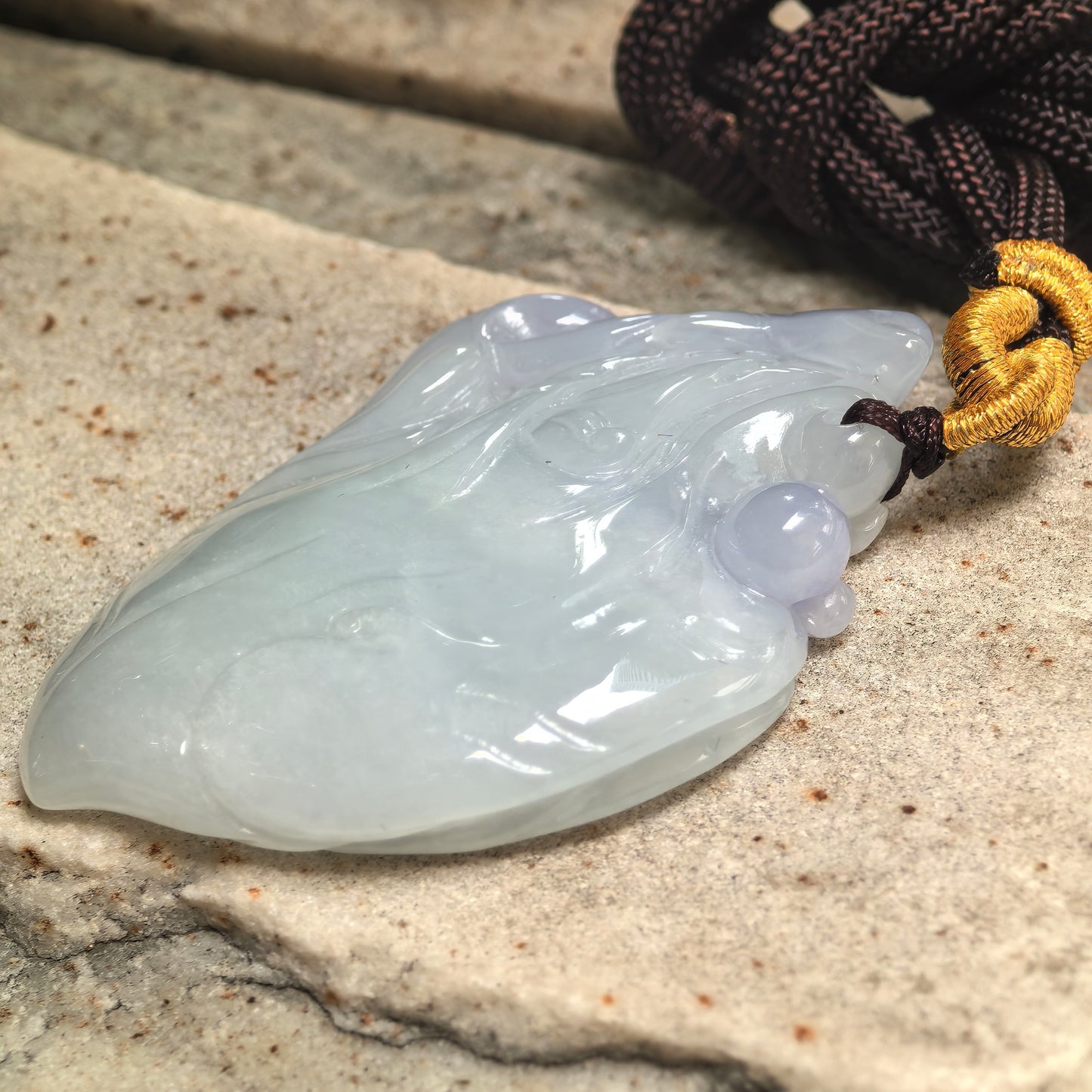 Side view of natural jadeite dolphin pendant showing raised carving, curved wave lines, and smooth thickness.