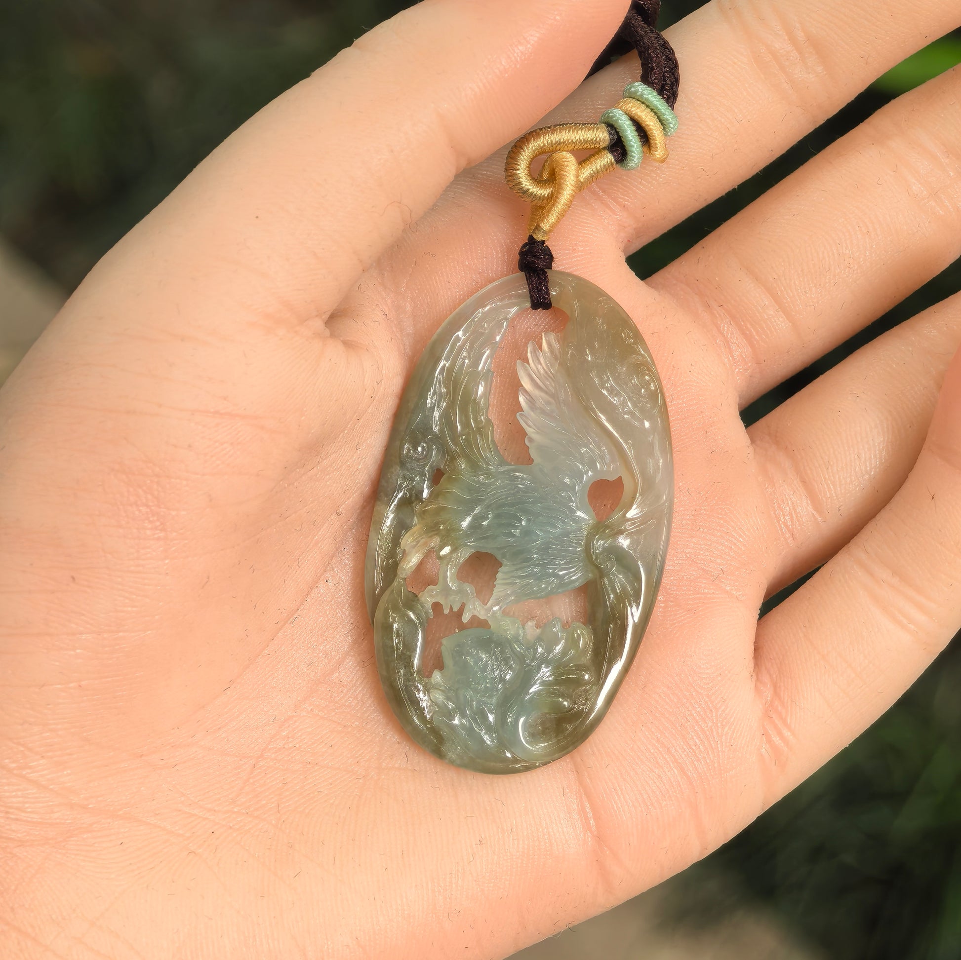 Yellow-brown and pale green jadeite pendant carved with eagle catching fish motif.