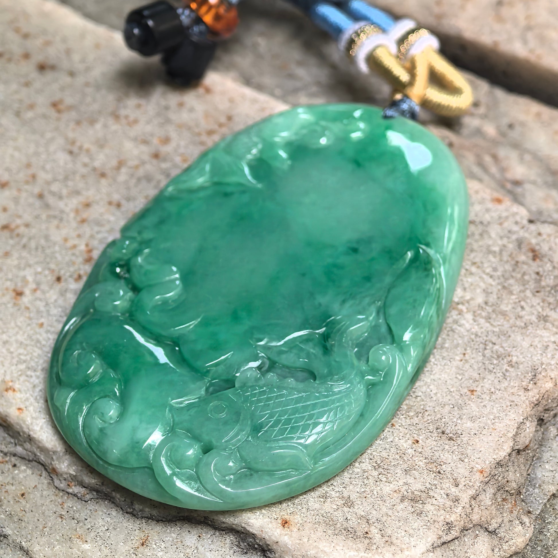 Side view of large green jadeite pendant showing slim plaque thickness and polished surface.
