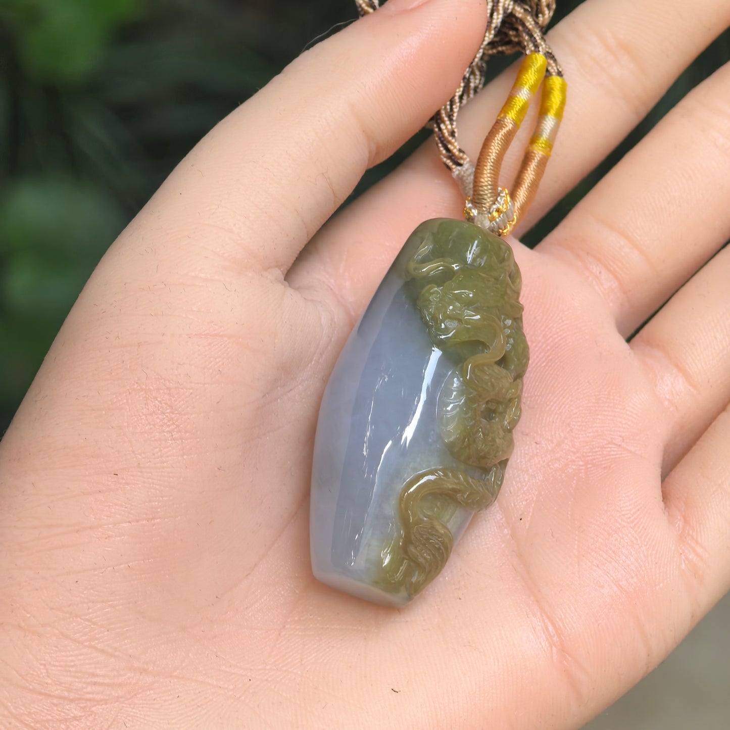 Jadeite dragon column pendant displayed in hand, showing yellow, light lavender, and light green color variation.