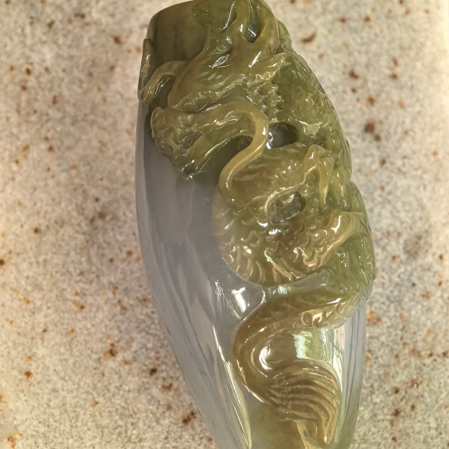 Close-up of yellow jadeite dragon pendant showing detailed dragon head, scales, and glossy polished surface.