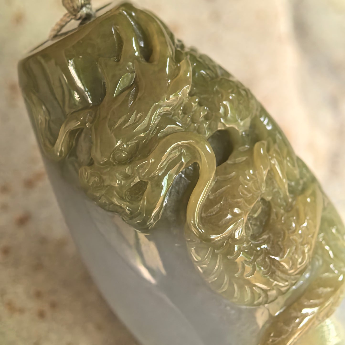Natural Grade-A yellow dragon column jadeite pendant shown at an angle with cord and smooth glutinous texture.