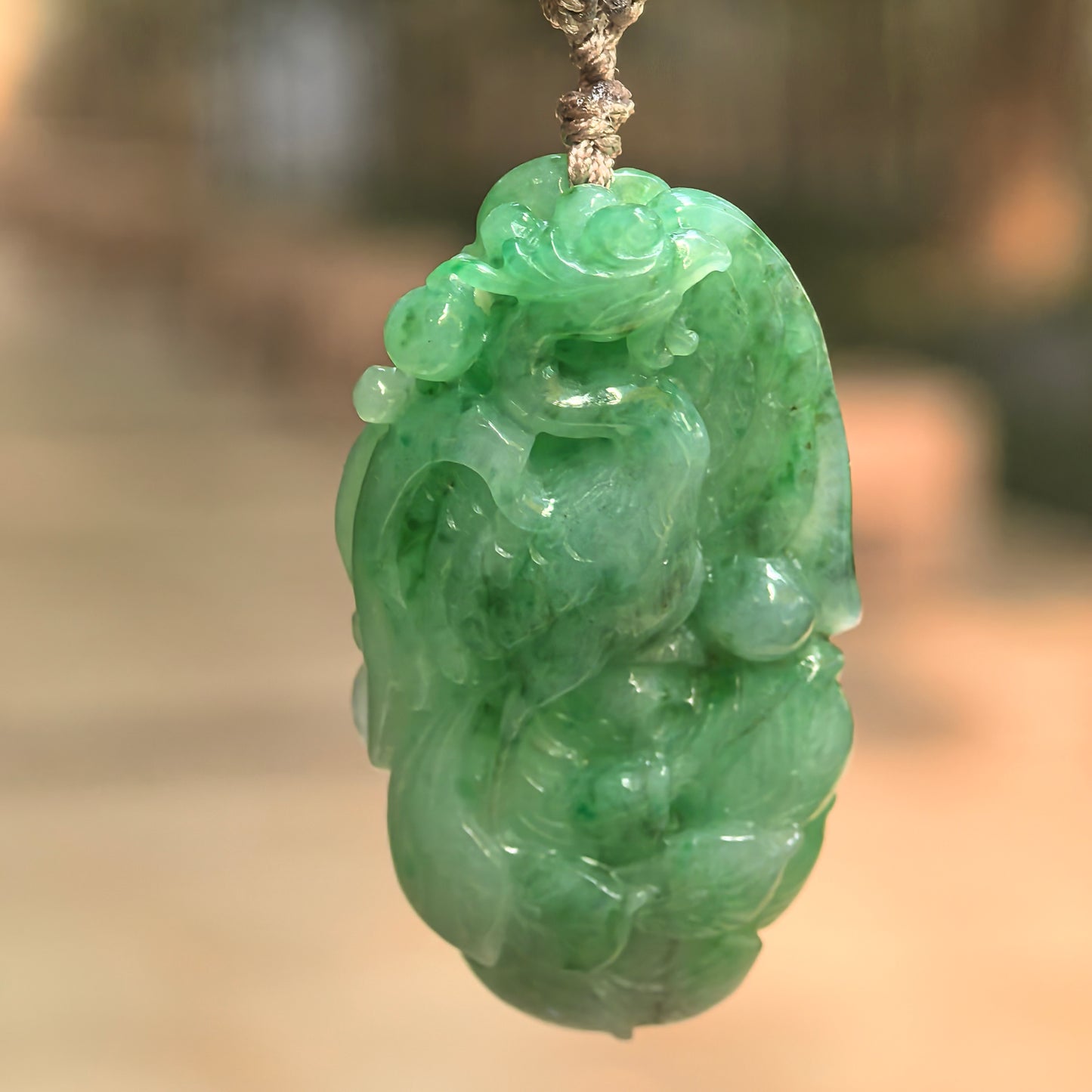 Natural Grade-A glutinous green phoenix jadeite pendant hanging on cord with vivid green color.